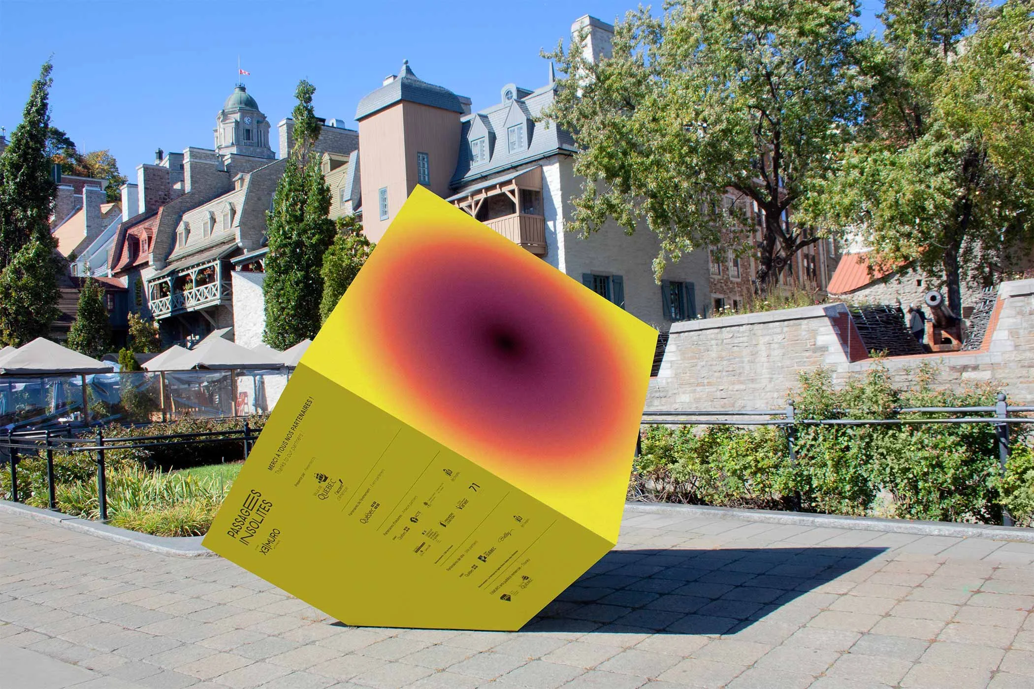 Cube servant de signalétique durant l'événement Passages Insolite posé devant des bâtiments anciens du Vieux-Port de la ville de Québec.