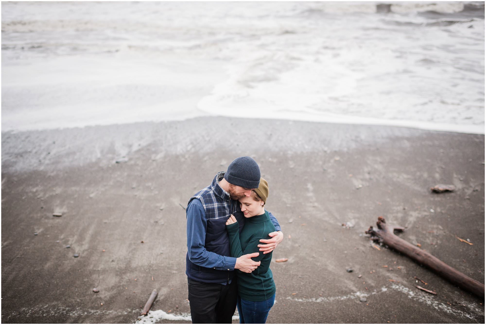  A couple cuddling while the tide comes in during their adventure elopement session in the PNW. 