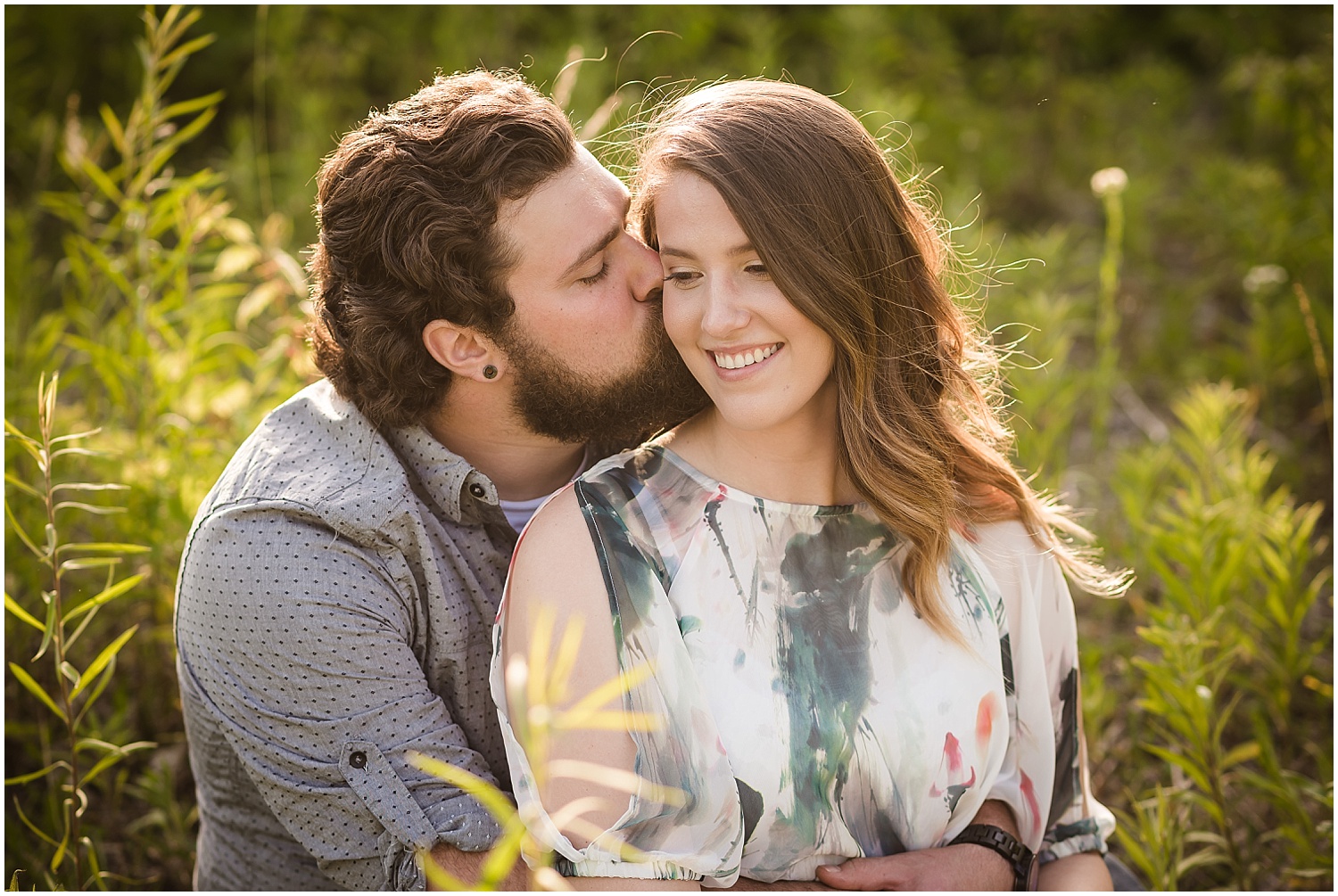  A brunette man kissing his brunette girlfriend in a brightly lit Monroe filed at sunset.  