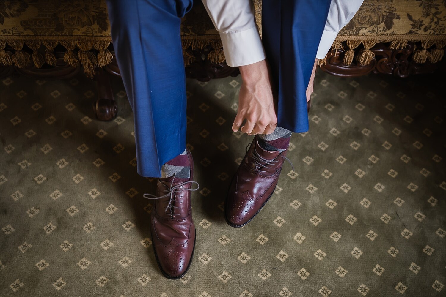  A close-up of a groom putting on his brown leather shoes.  