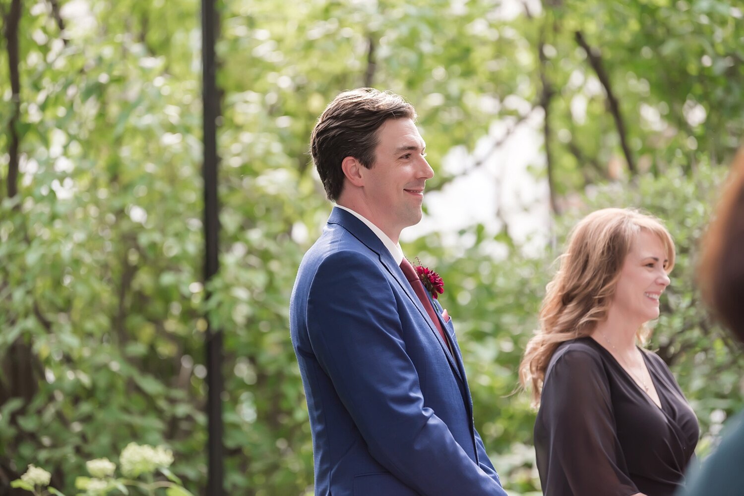  A groom waits for his bride while she walks towards him with her dad.  