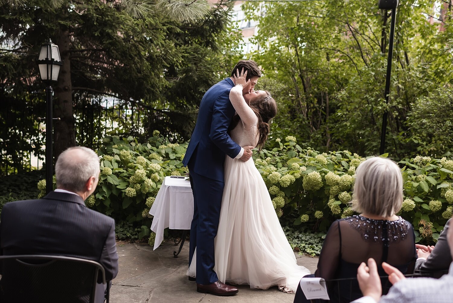  A couple share a passionate kiss during their outdoor courtyard wedding in Southeast Michigan.  