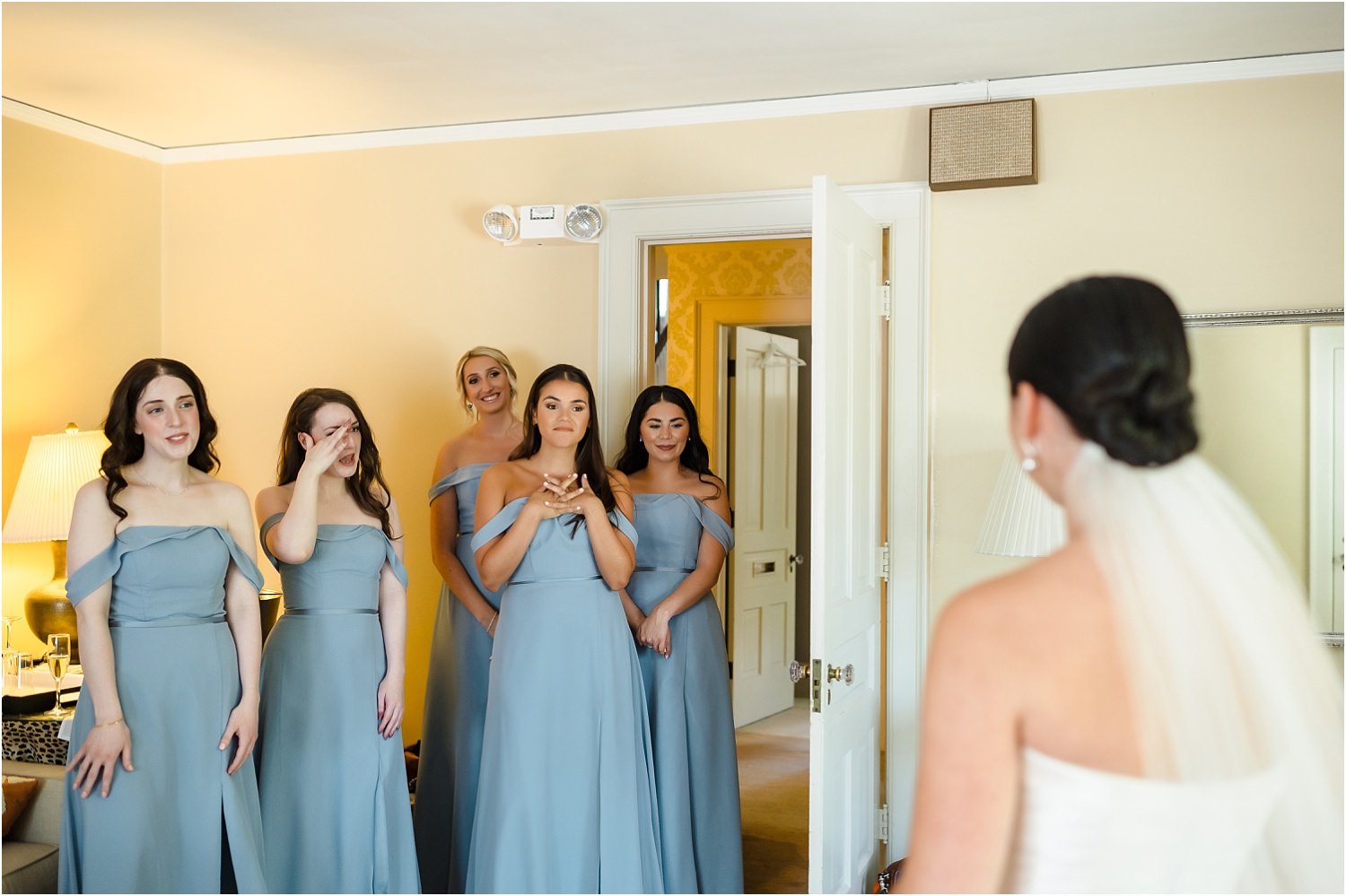  Bridesmaids wearing blue dresses happily react to the bride.  