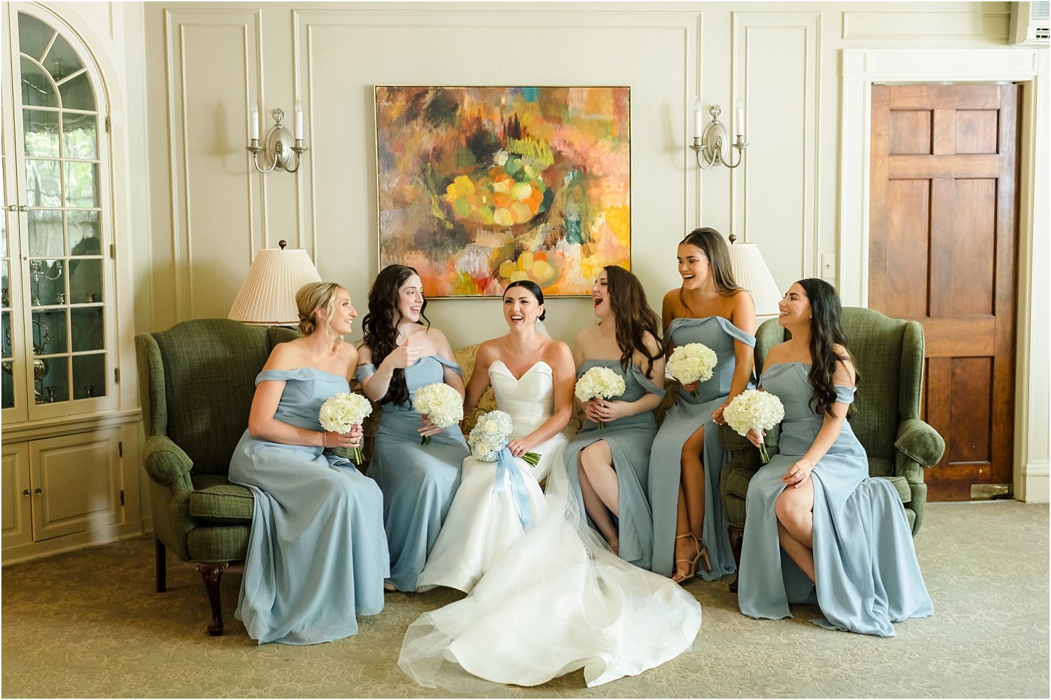  A bride and her bridesmaids sit in the Ann Arbor City Club and have a fun moment before the wedding ceremony.  