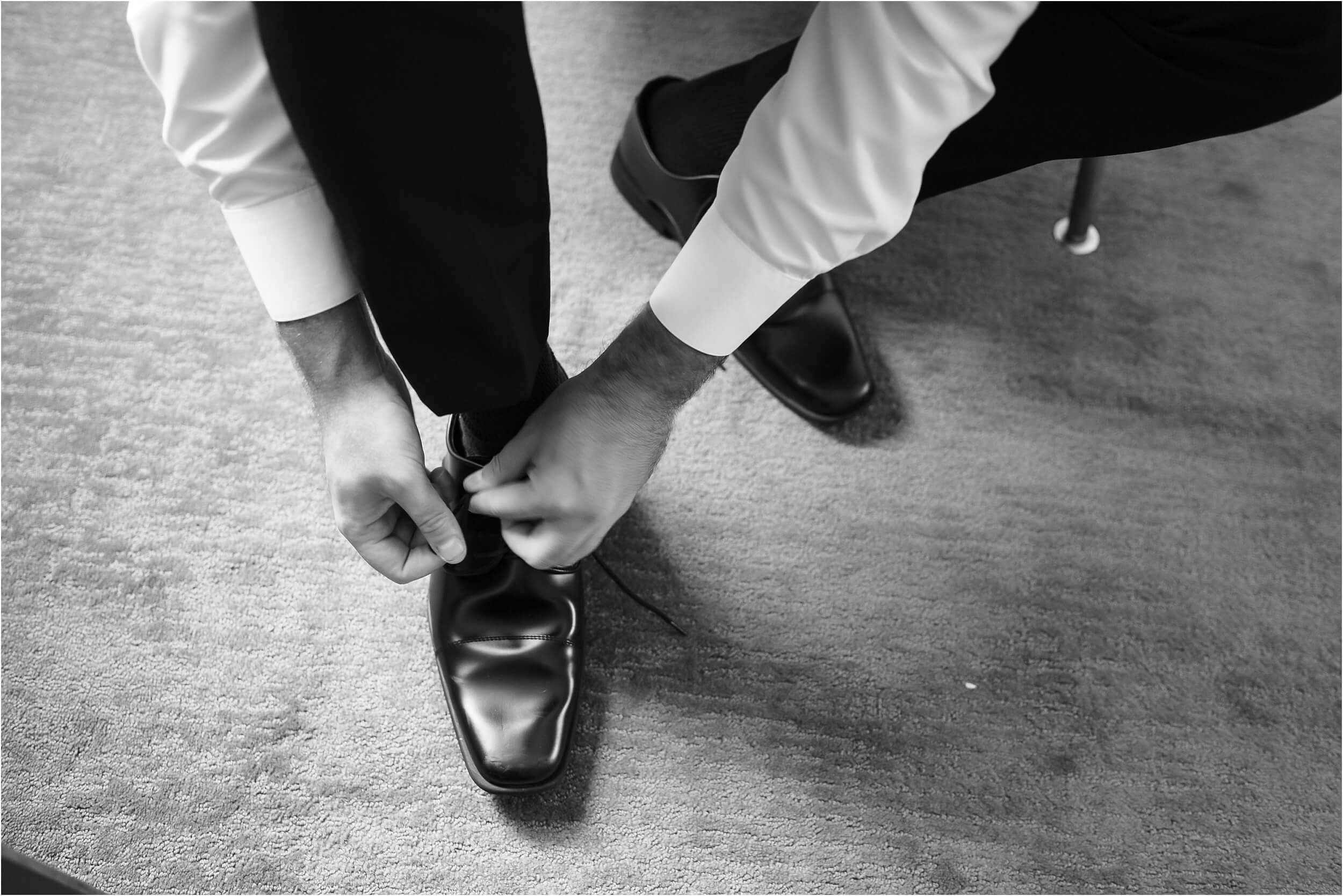  A close-up of the groom doing up his black leather shoes.  