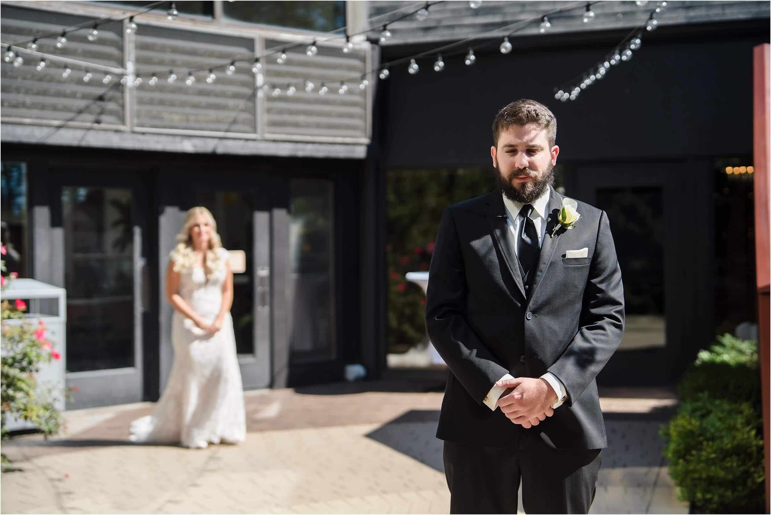  A groom waits patiently for his bride to sneak up on him for their first look in a courtyard.  