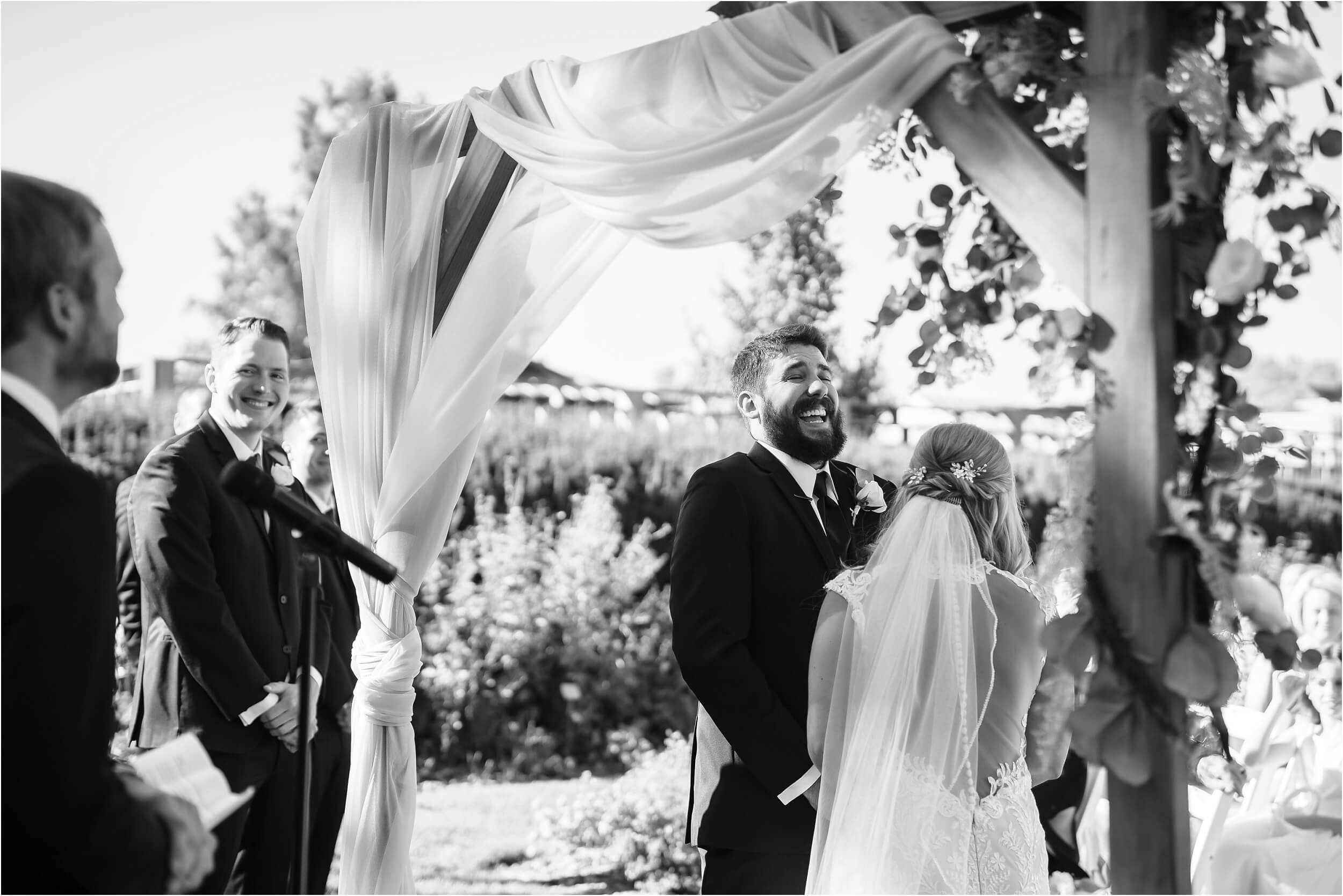  A groom laughs during his vows on a sunny summer day. 