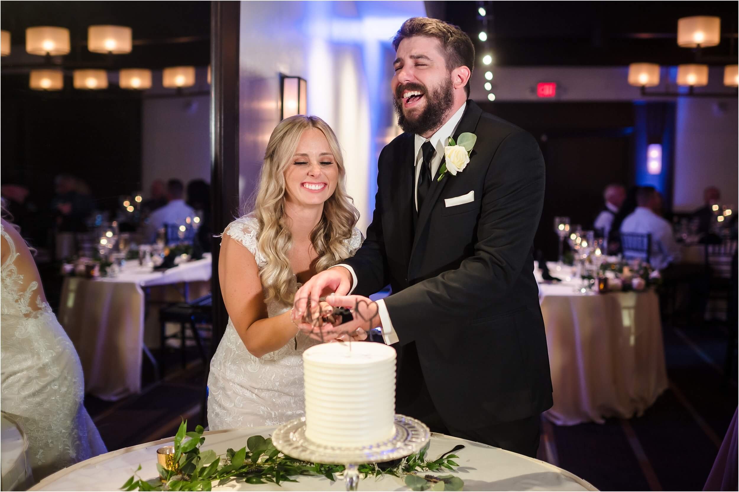  A couple laughing at their cake cutting at a hotel wedding reception venue near Ann Arbor, Michigan.  