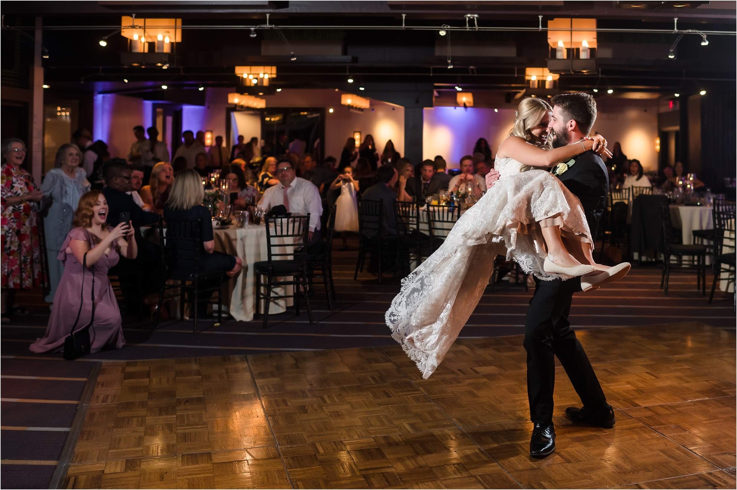  A groom lifts and dances with his bride during their first dance.  