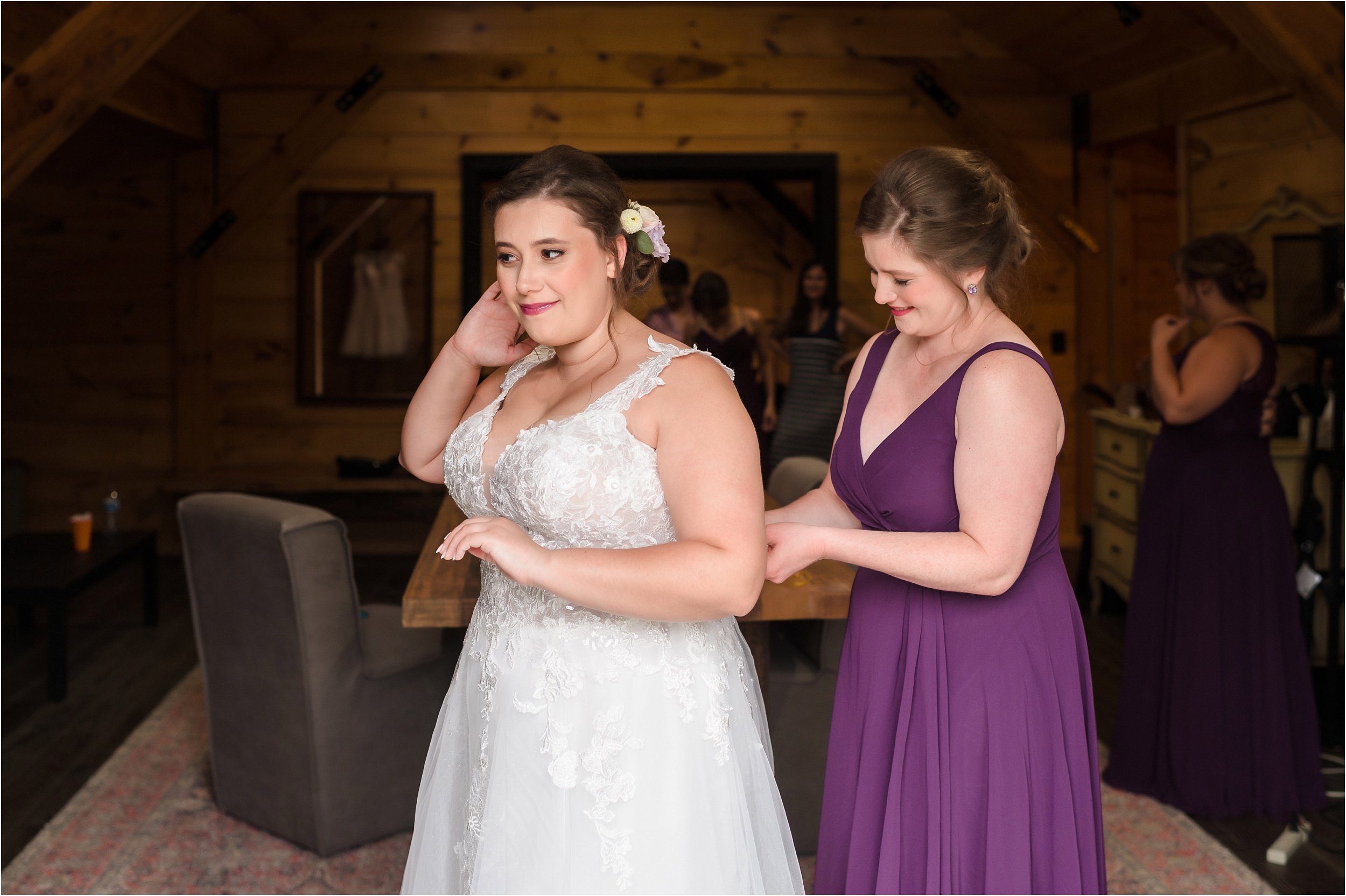  A bridesmaid helping the bride button up the back of her wedding dress.  