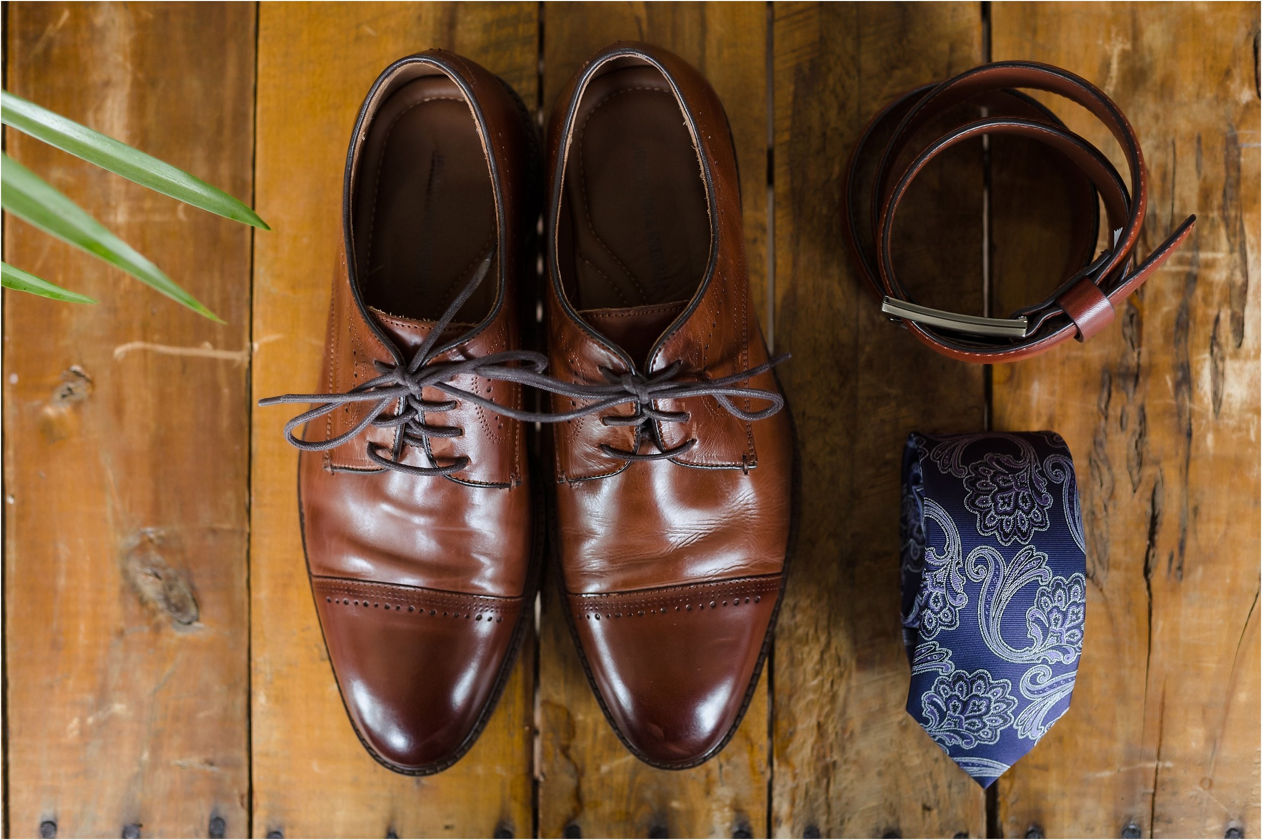  A layflat of brown leather shoes, a tie, and a belt.  