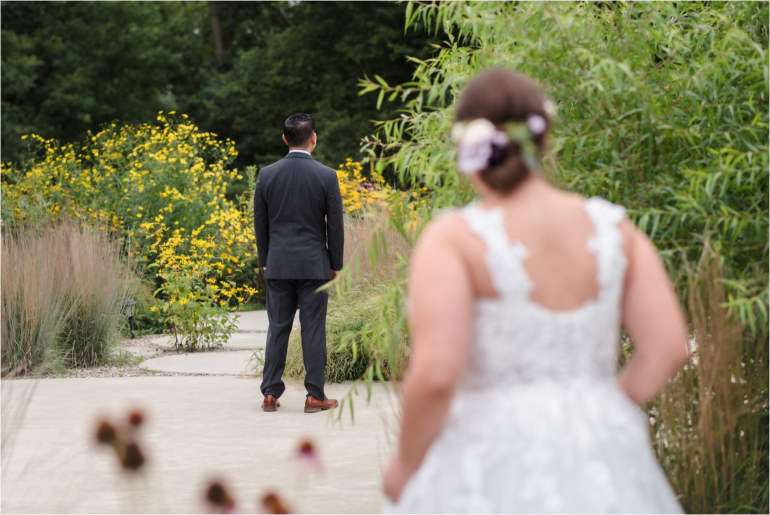  A bride peers around a bush before her first look.  