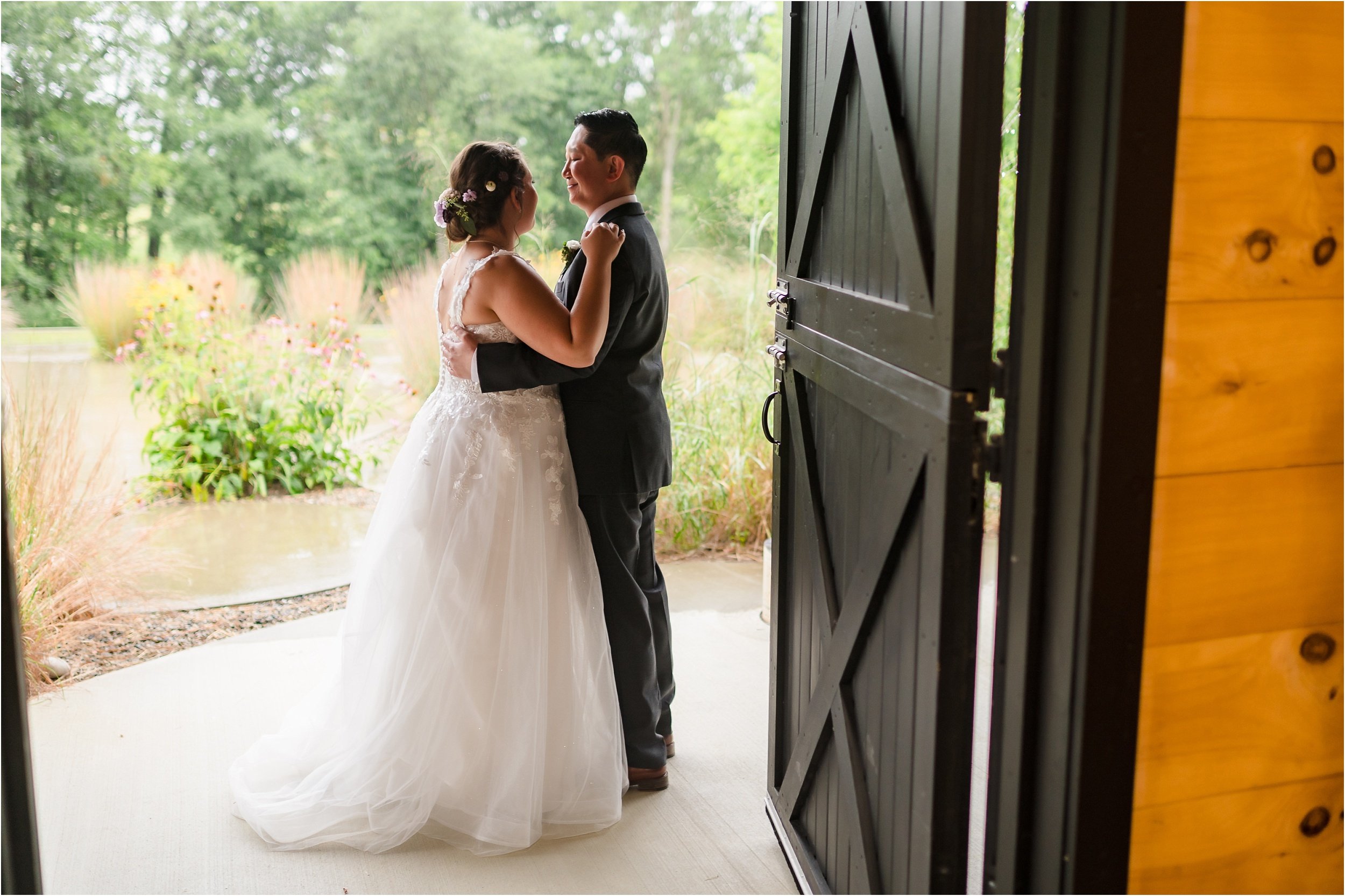  A couple watches the rain on their wedding day after their ceremony through a door.  