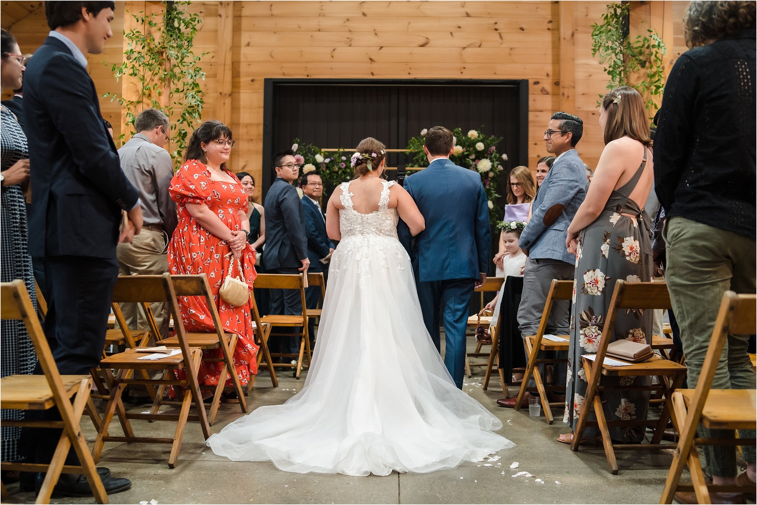  A back view of a bride with a long train walking down the aisle.  