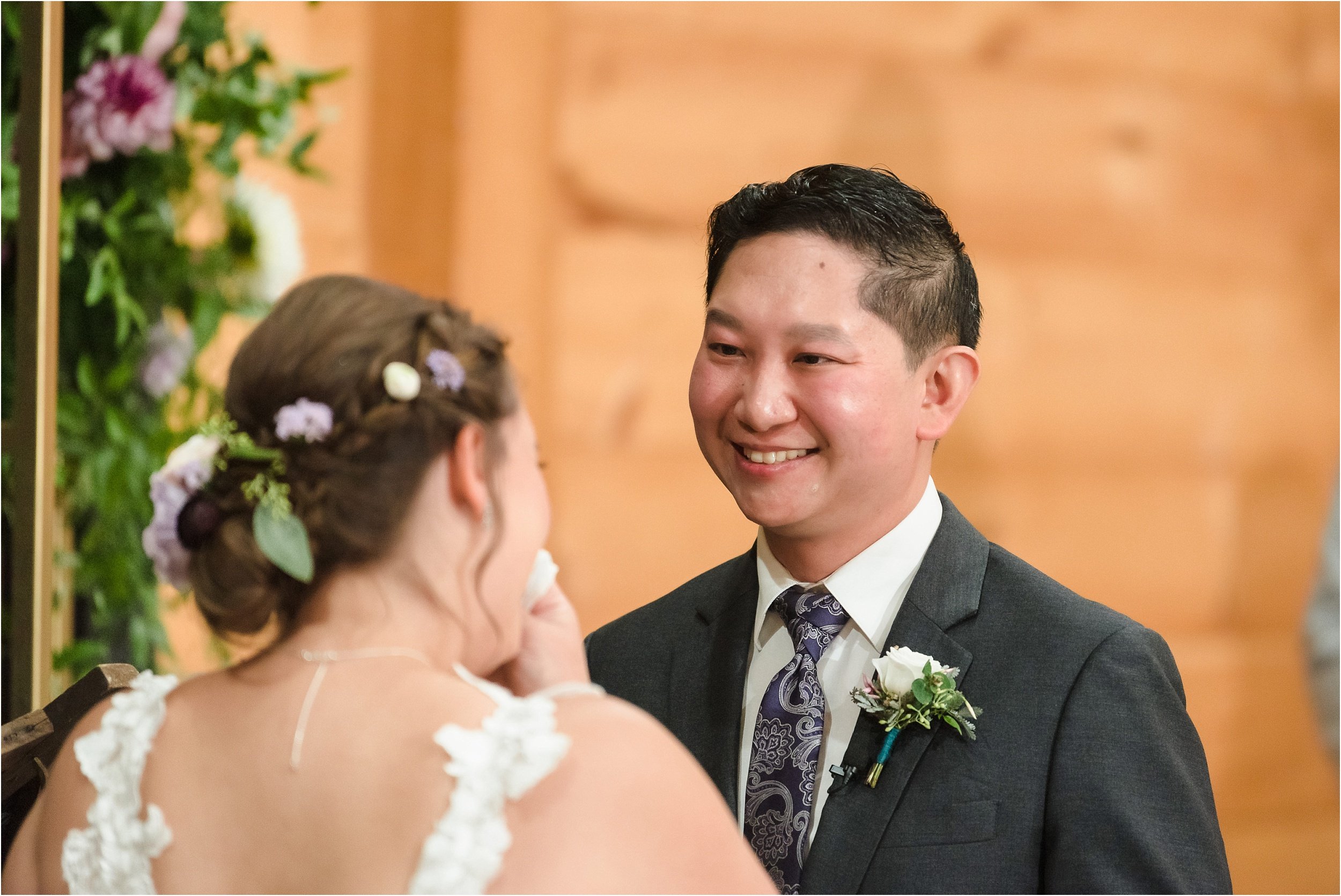  A man smiles at his soon-to-be wife while she reads her vows to him.  