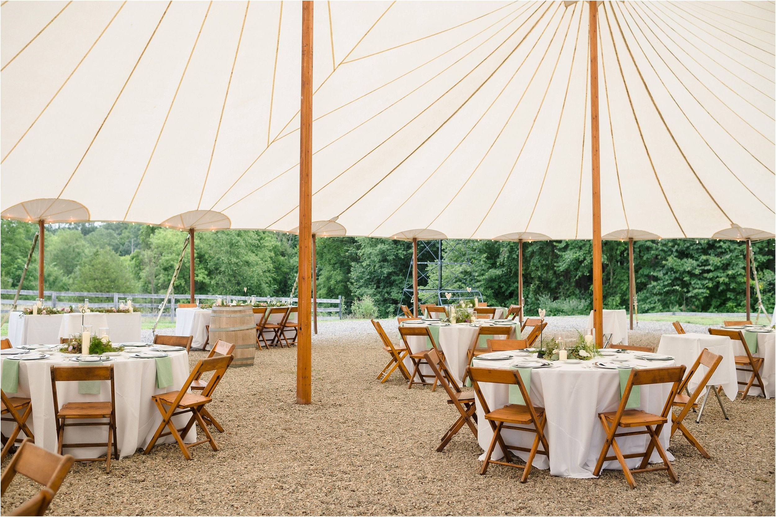   Tables and wood chairs set-up at a tent wedding reception.  