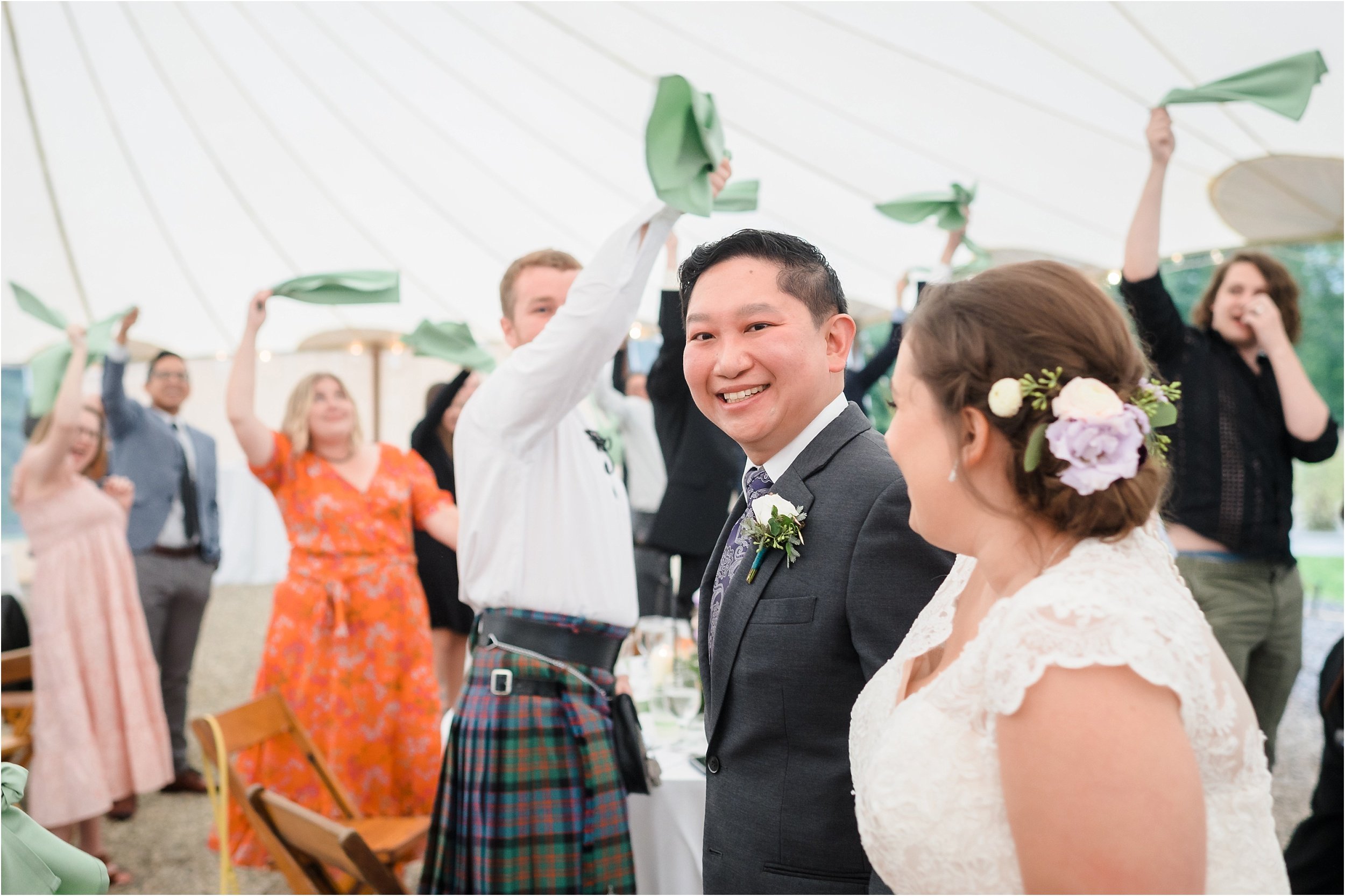  A groom smiles at his bride while they enter their reception to loud applause.  