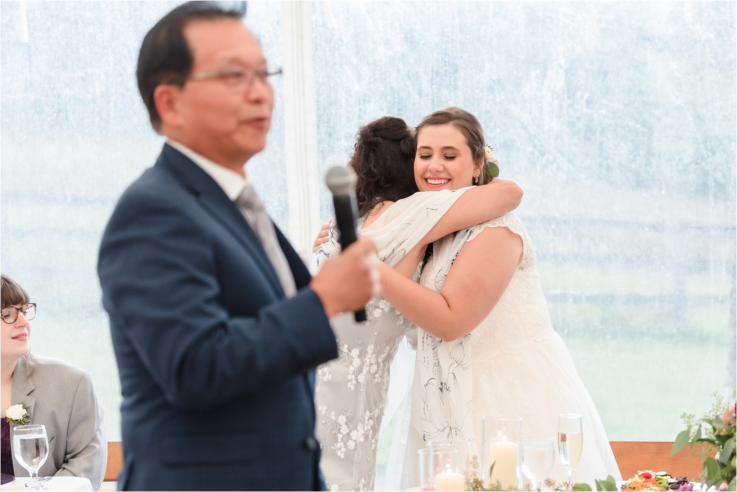  A bride hugs her new mother-in-law during her father-in-law’s speech.  