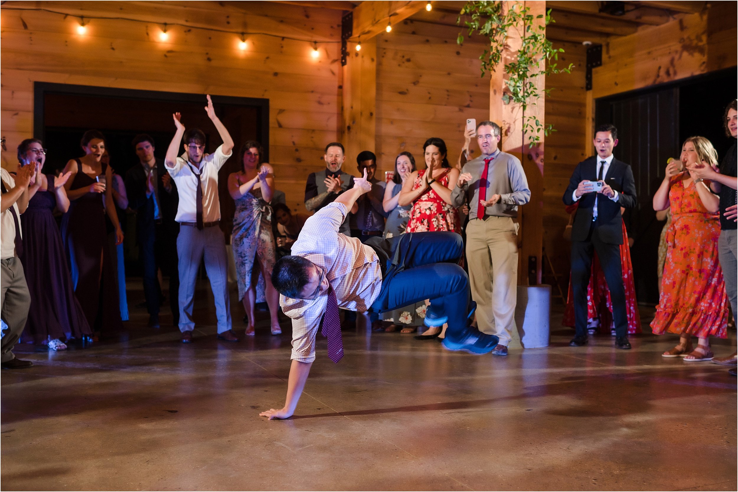  A groomsman break dances during a dance party after a wedding.  