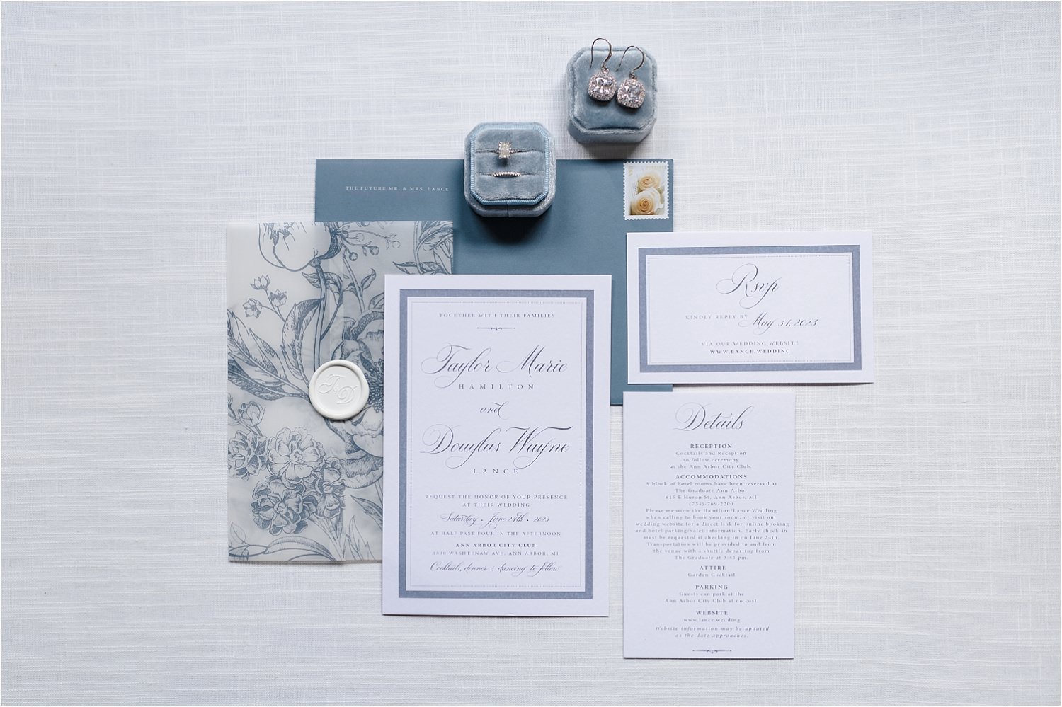  A blue and white wedding layflat with a floral invite and jewelry.  