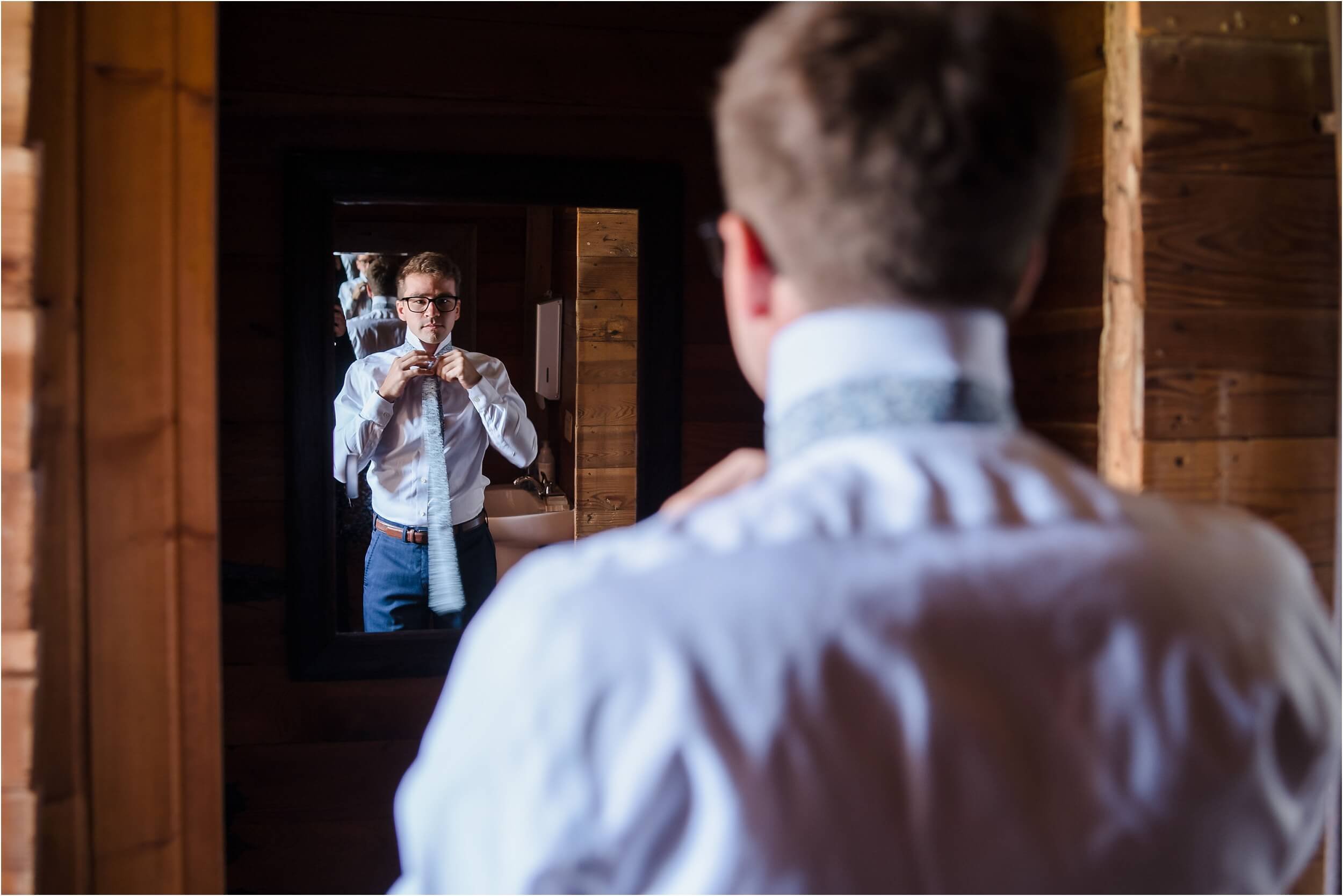  A groom slowly does his tie in the mirror of a historic barn in Washtenaw county.  