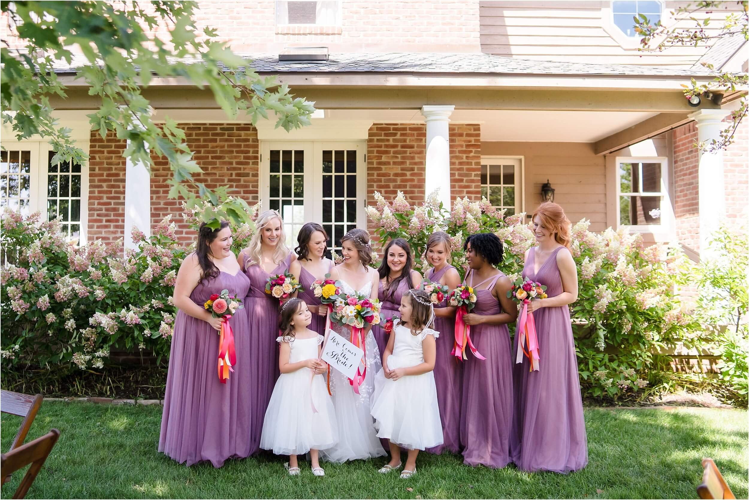  Five bridesmaids, two flower girls, and a bride all talk during their portrait session at a popular wedding venue in ann arbor.  