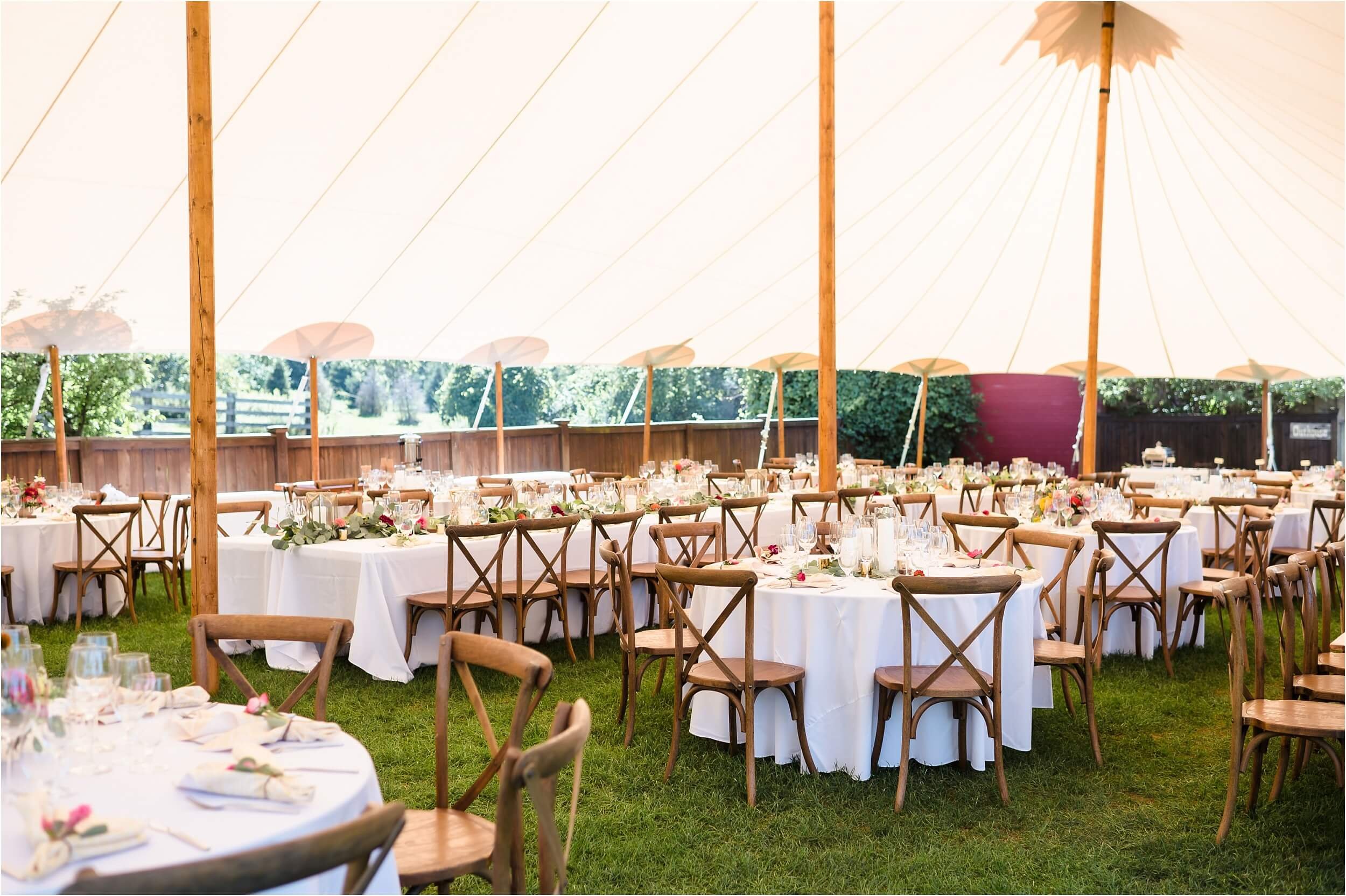  A tented reception with wooden rustic chairs at Frutig Farms. 