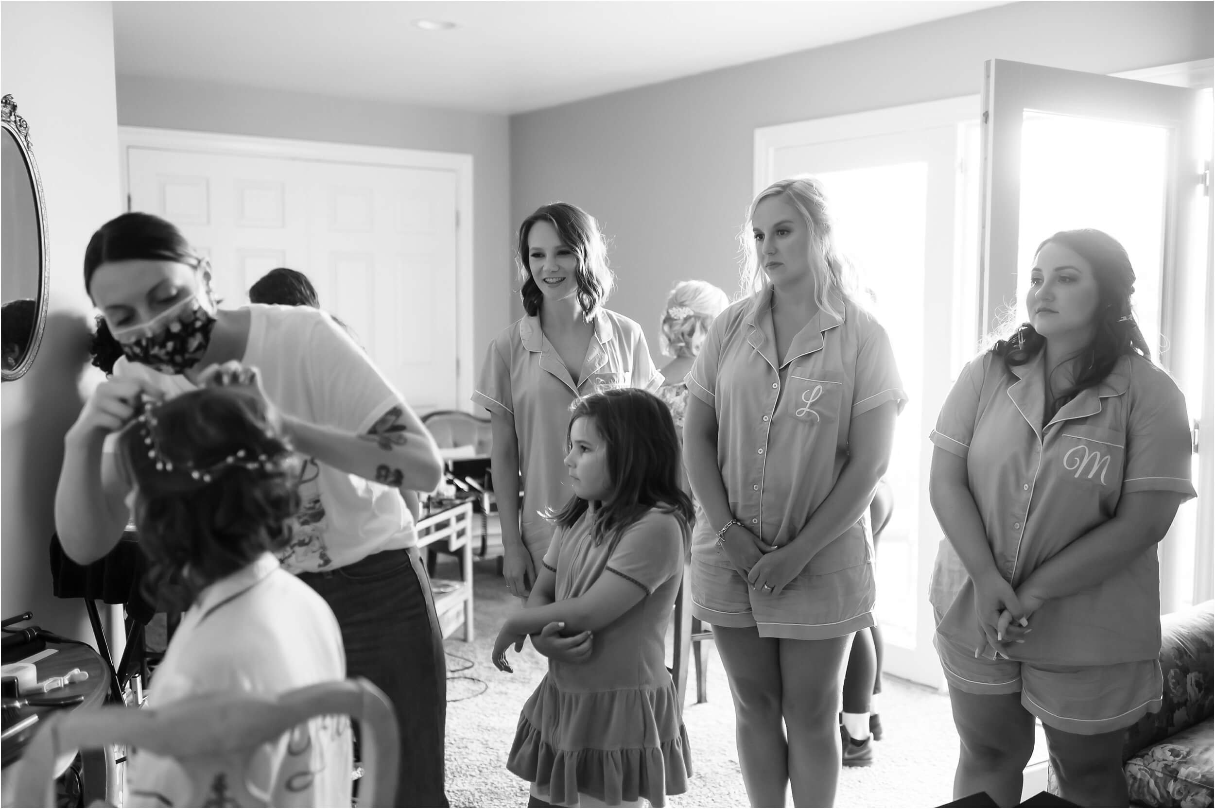  Bridesmaids looking on lovingly as their friend, the bride, finishes up hair and make-up. 