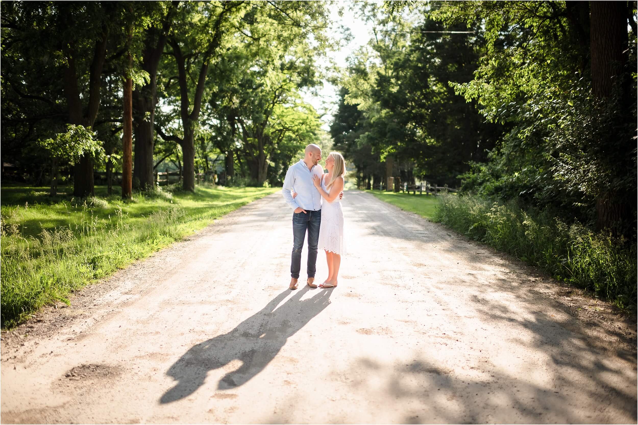  A couple walks down a dirt road during their June engagement session.  