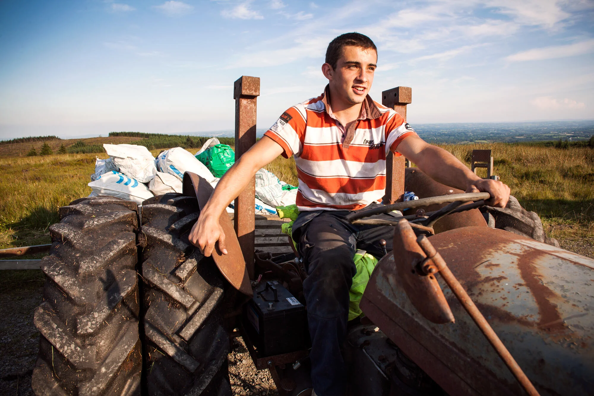 Damian McClave drives the tractor for his neighbor bringing bags of turf home. 