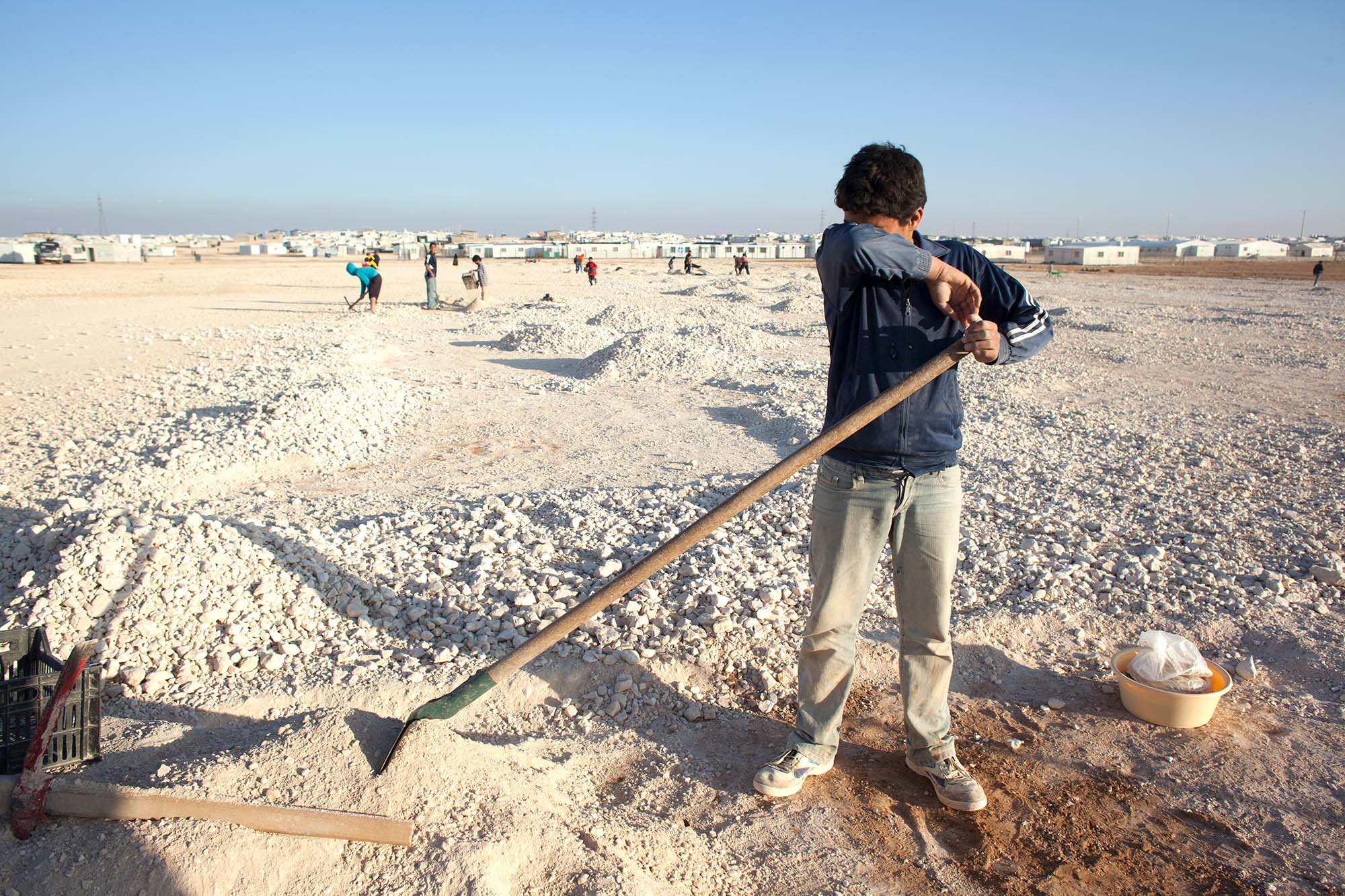  A young boy wipes the sweet from his brow as he shovels dirt to make building blocks.&nbsp; 