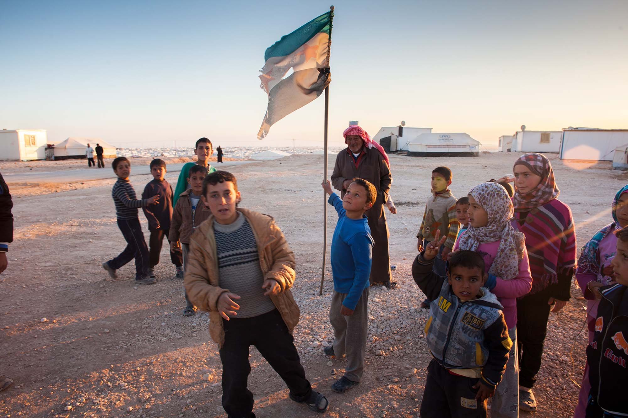  A young boy flies the Syrian opposition flag in Zaatari refugee camp.&nbsp; 