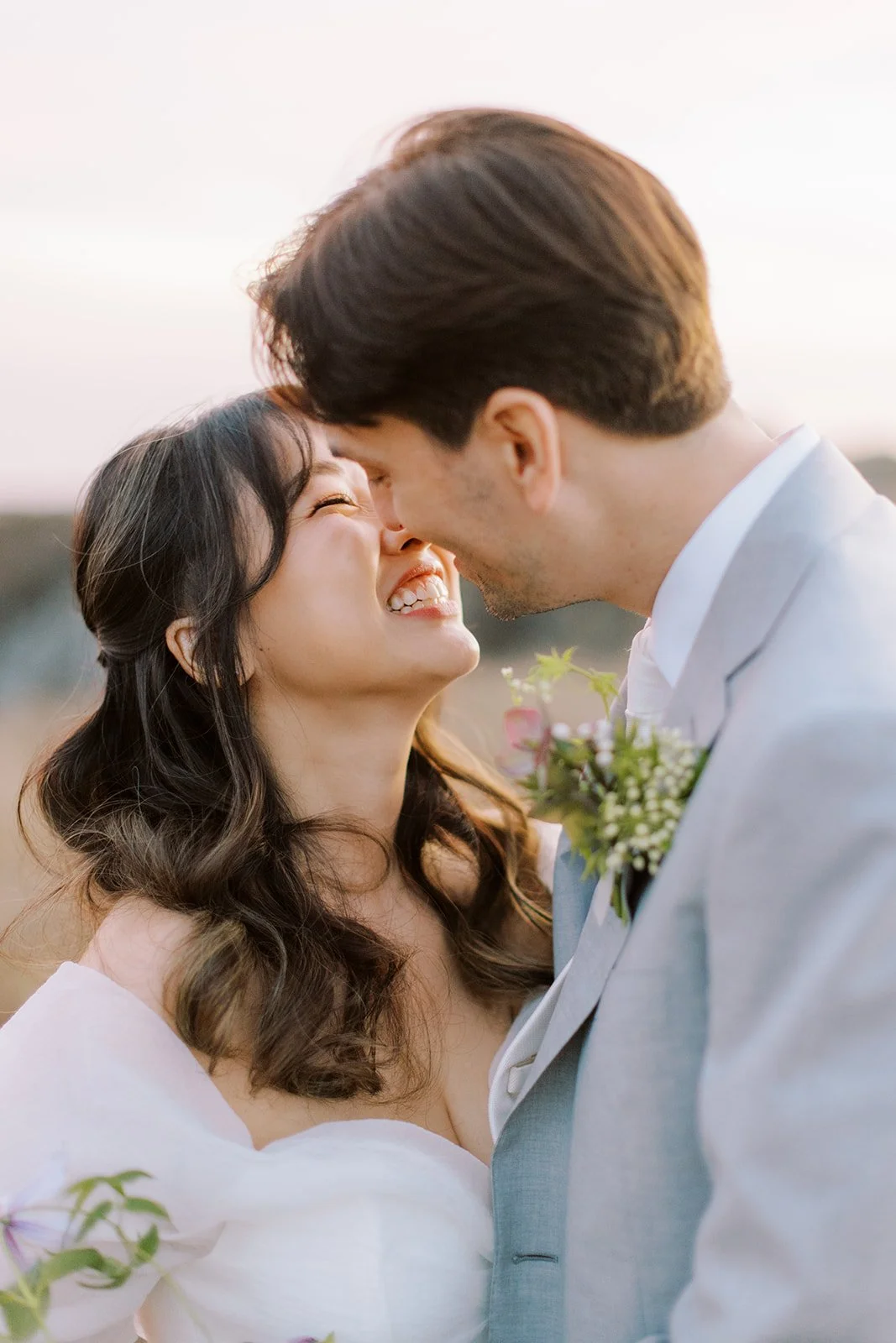 Tight shot of a wedding couple embracing in the glow of the sunset.