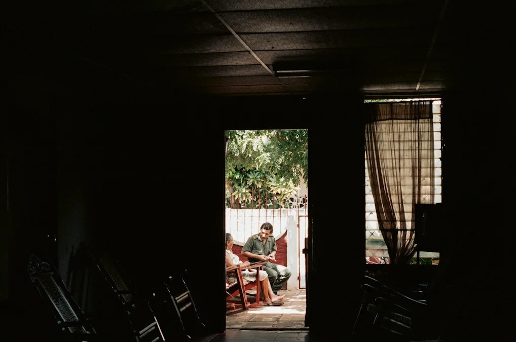 Doña Mercedes sits on the front patio with her son Julio.