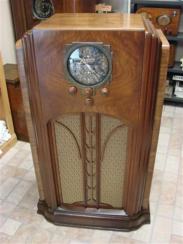 This is a 1936 Zenith 9 tube model 9S55, one of Zenith’s best collectable years. The large black dial is in very nice shape. This cabinet definately has that "empire"(skyscraper) look with that nice bottom border as a strikeing foundation. This particular model has a small footprint, with a tall & lean look to it. The cabinets’ book matched walnut veneer is beautifully restored with a flawless lacquer finish and toned lacquer color trim. The grille cloth is a reproduction of the 1936 pattern found on these models.