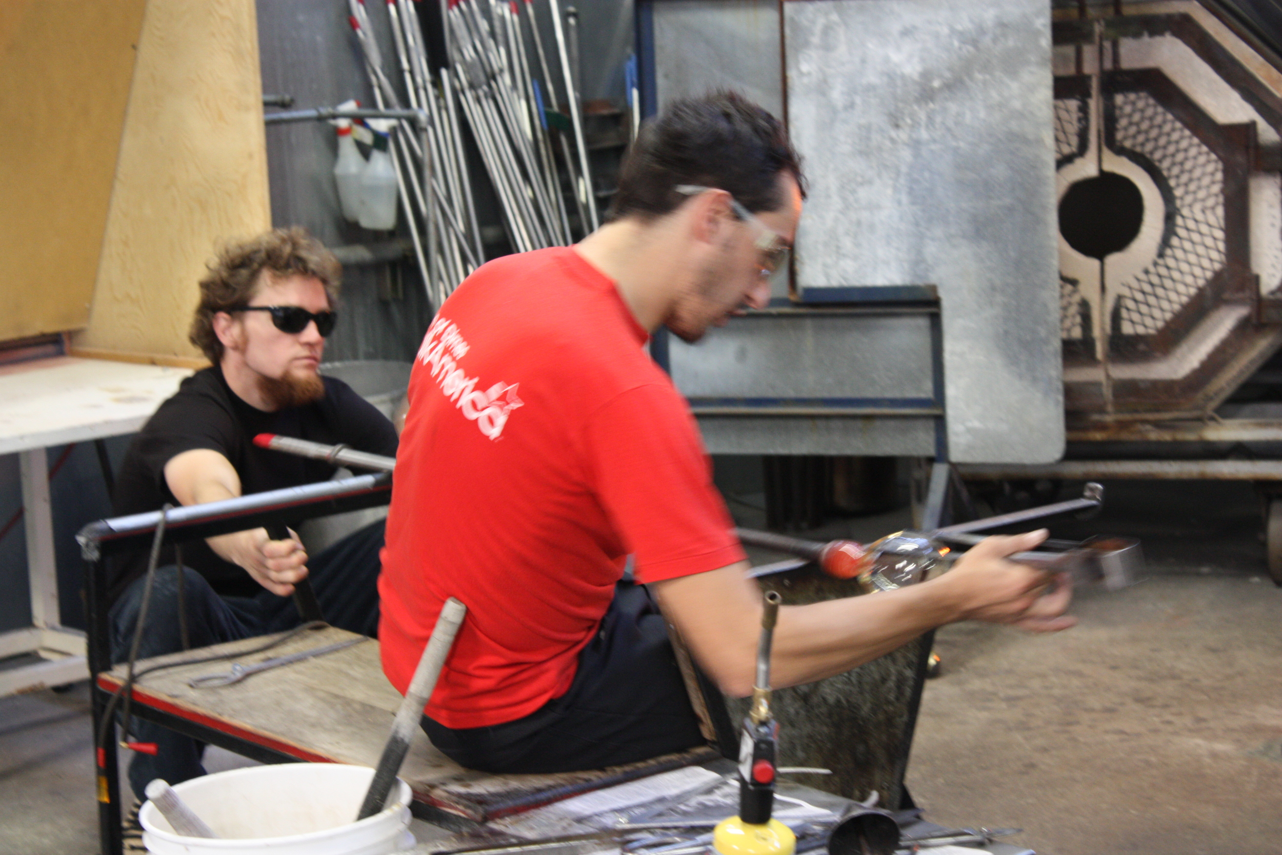   Esteban recruited fellow glassblower Morgan Chivers to assist him. After watching the two work together, I understand why you could never do glassblowing alone. In the picture above, Morgan is waiting for Esteban to signal that he should blow more 