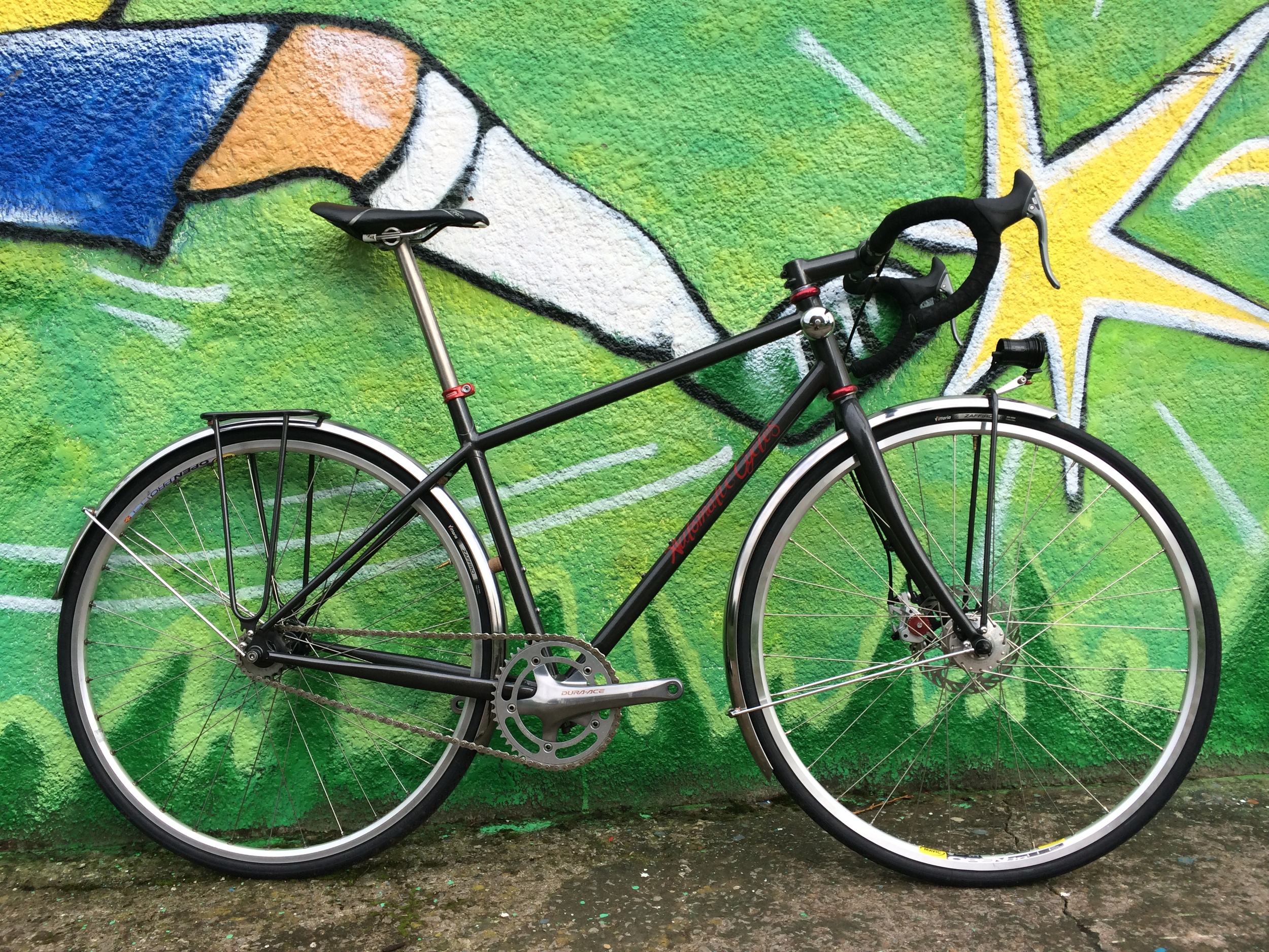 John's Commute bike fixed gear compact frame for daily use on roads and dirt tracks. Custom built rack and Exposure Revo mount.