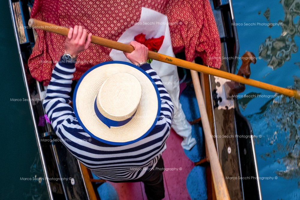 A gondolier rows his gondola with a bunch of red roses on April 25th. During Republican times, it was tradition that on April 25th (St Mark's holy day), a red rose blossom be offered to one's beloved as a token of love. The tradition allegedly starte