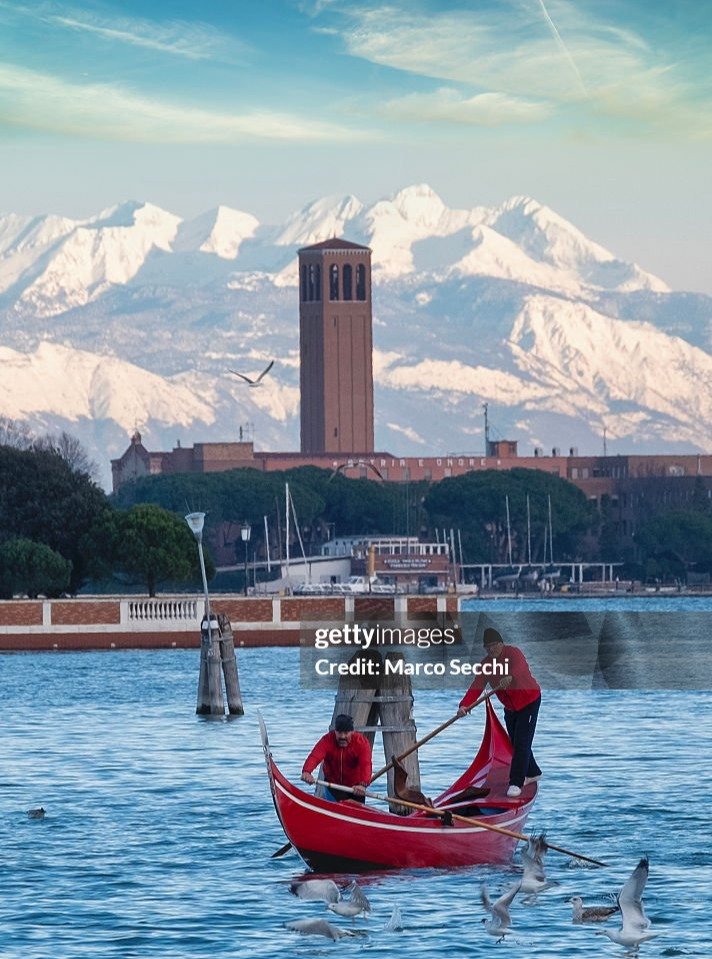 Oh yes, you can catch it 😄

Venice is playing tricks again.

A red gondola slicing through blue water, seagulls causing chaos, and snow-covered mountains quietly stealing the background.

Not the postcard angle.

Still 100% Venice.

Shot with Leica,