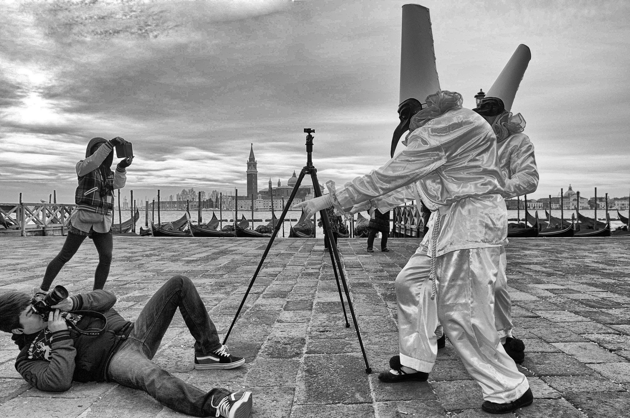 Venice, Carnival season.
Everyone thinks the masks are the spectacle. The real theatre is the dance between photographers, tripods, bad knees, questionable dignity, and a shared agreement that this moment is worth looking ridiculous for.

This is wha
