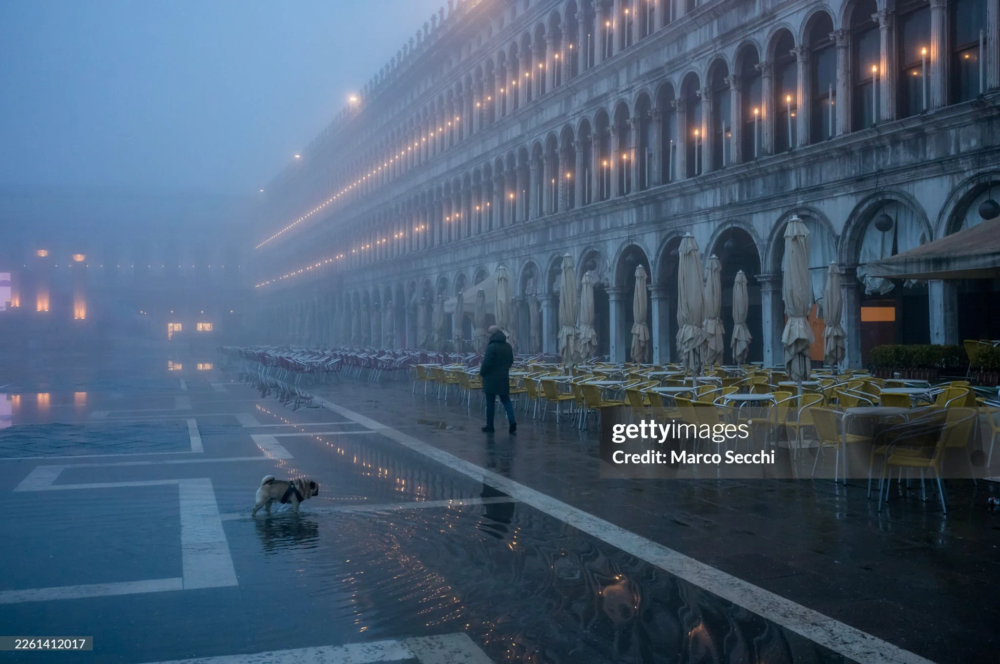 There are mornings in Venice when the city feels like it is still deciding whether to exist.
San Marco, usually loud with footsteps, voices, and cameras, reduced to the sound of water moving across stone. The caf&eacute;s empty. The chairs waiting. T