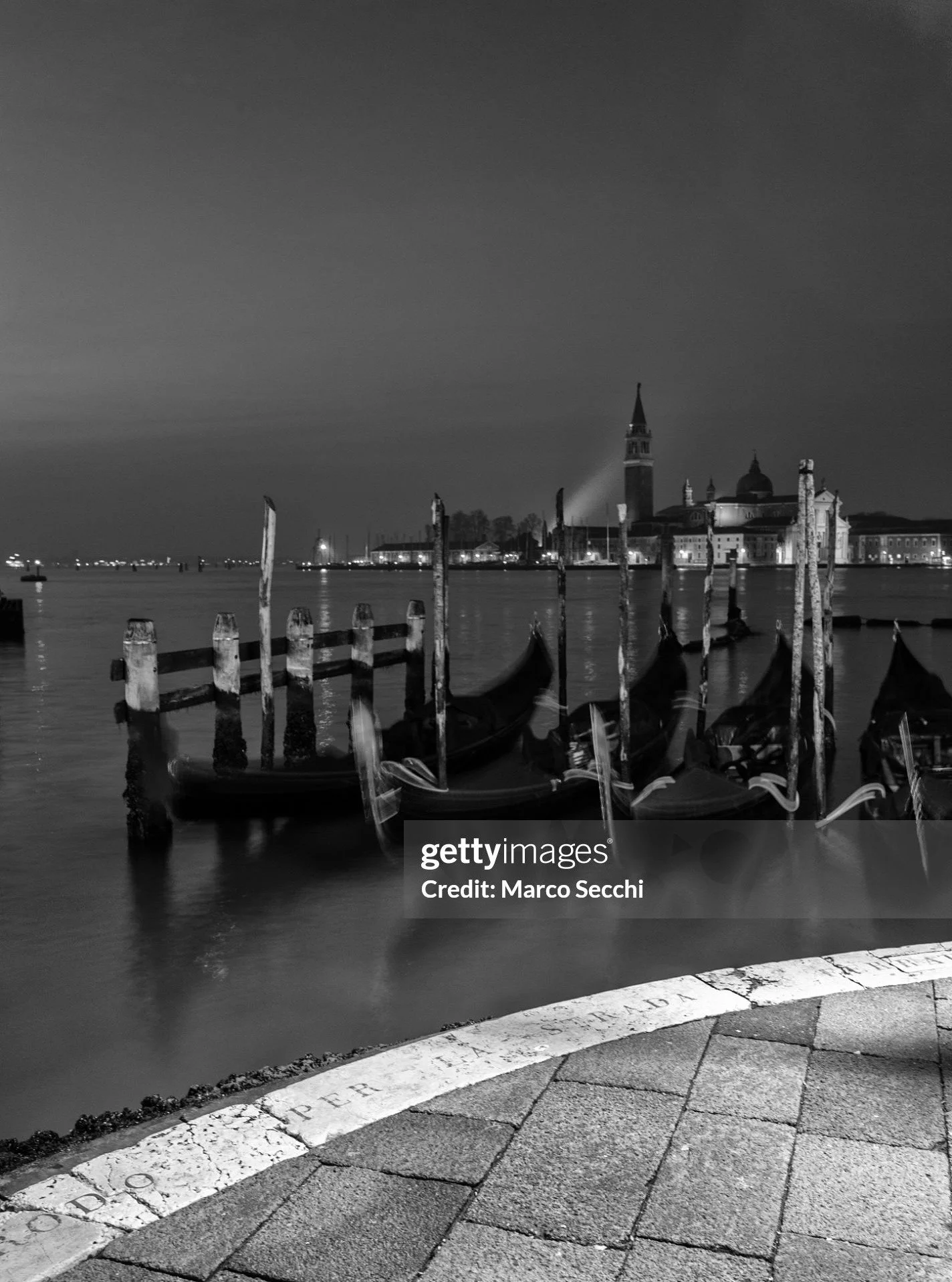 VENICE, ITALY &ndash; March 6, 2026: Long-exposure black and white photograph of the historic landing stage known as the "Approdo per la Strada Ferrata" on the Bacino di San Marco waterfront. 
The structure was built in the 19th century to 