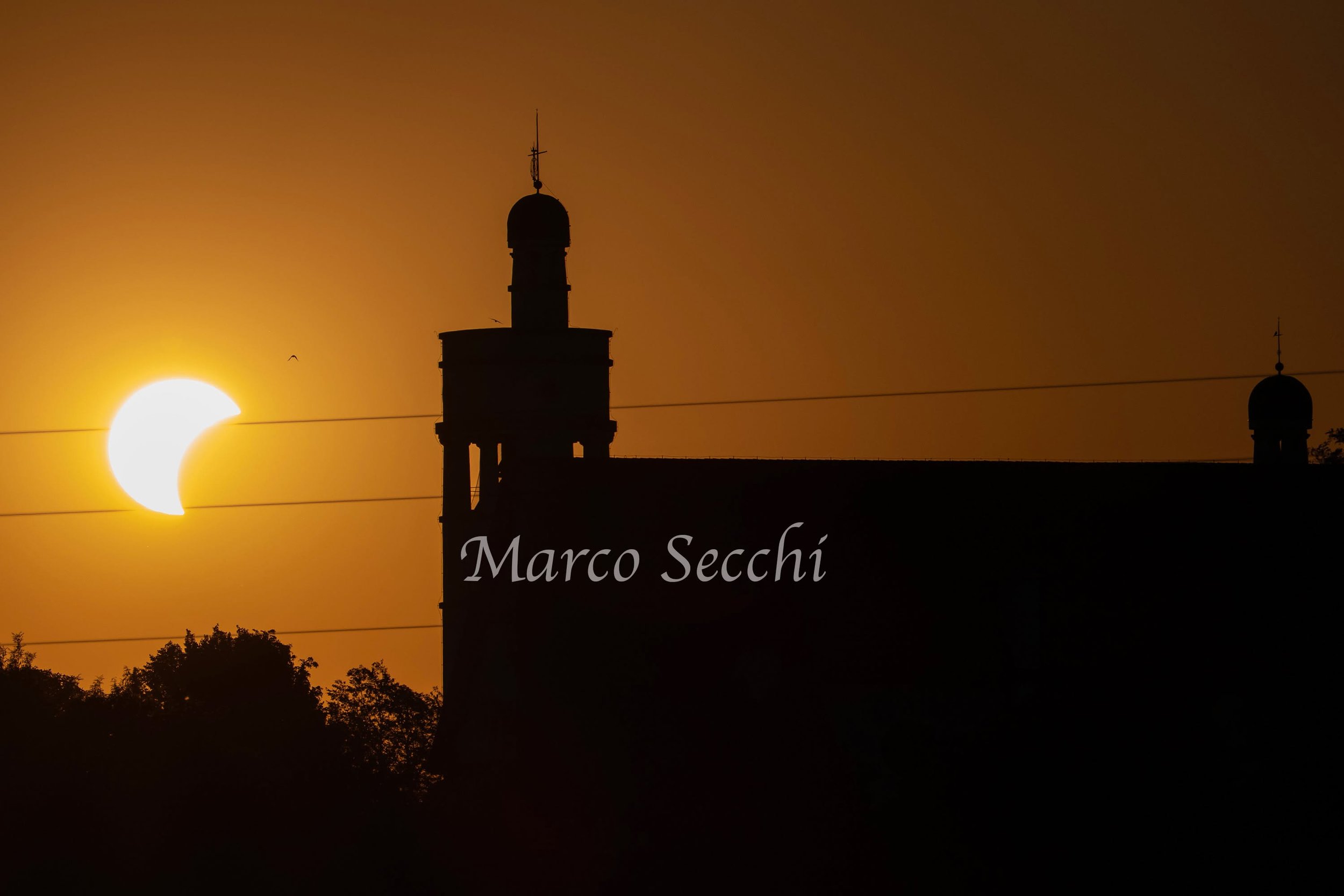 BOGOJINA, SLOVENIA - AUG 12 2026: A partial solar eclipse is seen alongside the Church of the Ascension of Christ in Bogojina, Slovenia. The landmark church was designed by renowned Slovenian architect Jože Plečnik and built in the 1920s, incorporati