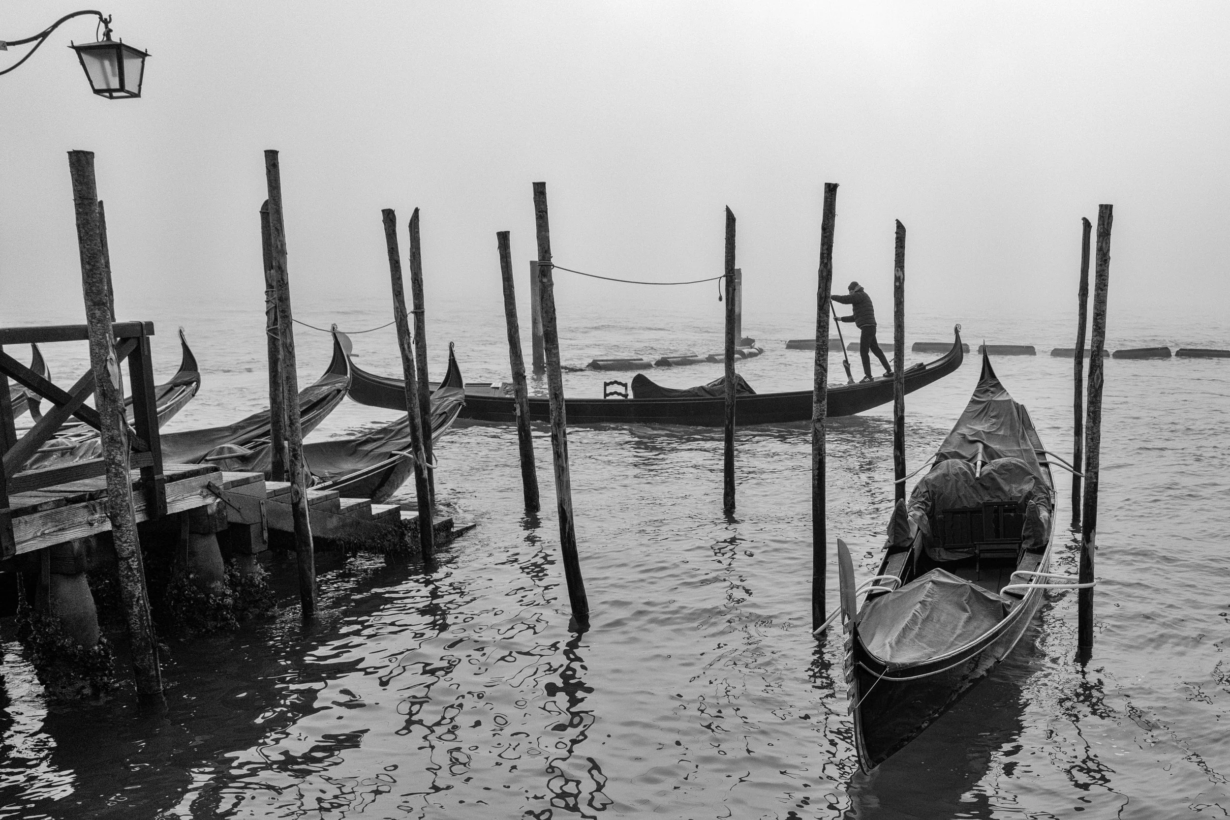 Venice is often photographed for what it reveals. On mornings like this, it becomes more interesting for what it hides.

Fog removes the familiar landmarks and leaves only rhythm: gondolas, wooden poles, reflections, and one gondolier moving through 