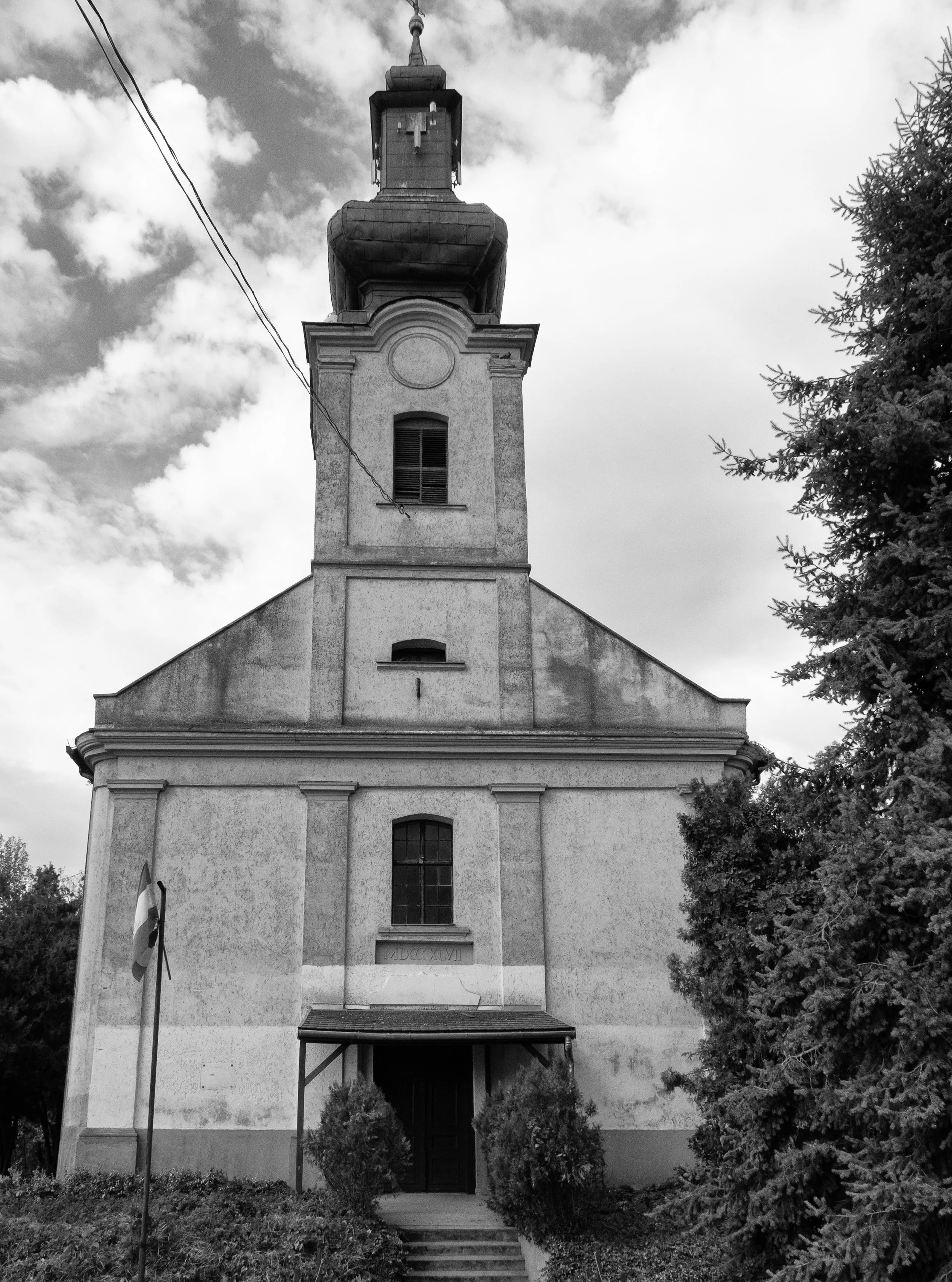 The Nagyr&eacute;vi Reform&aacute;tus Templom has stood here since 1847. Its tower watched over baptisms, marriages, funerals and the quiet procession of ordinary Sundays. 

Decades later, as darker events unfolded behind the village's closed doors, 