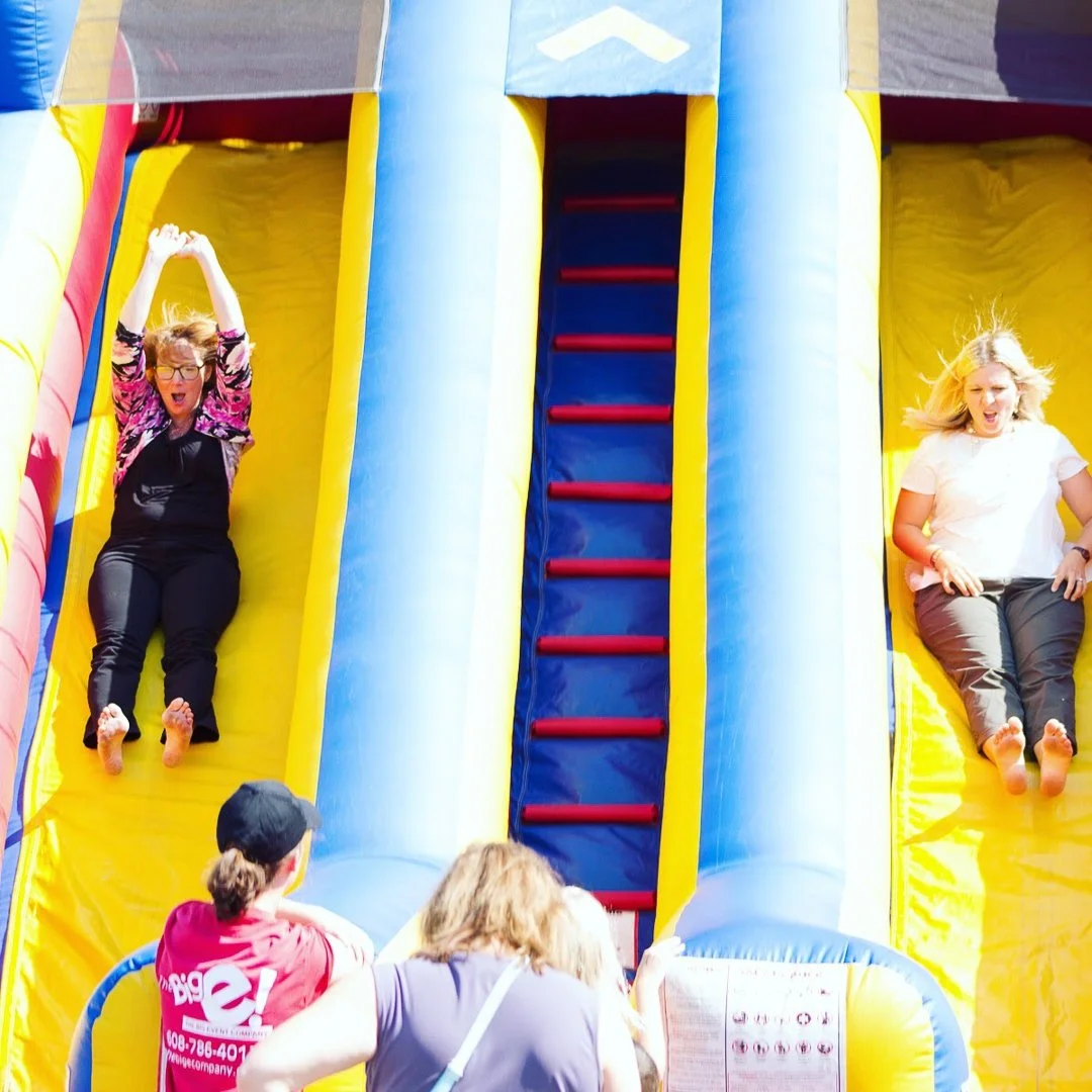 Photo of women smiling and sliding down an inflatable slide