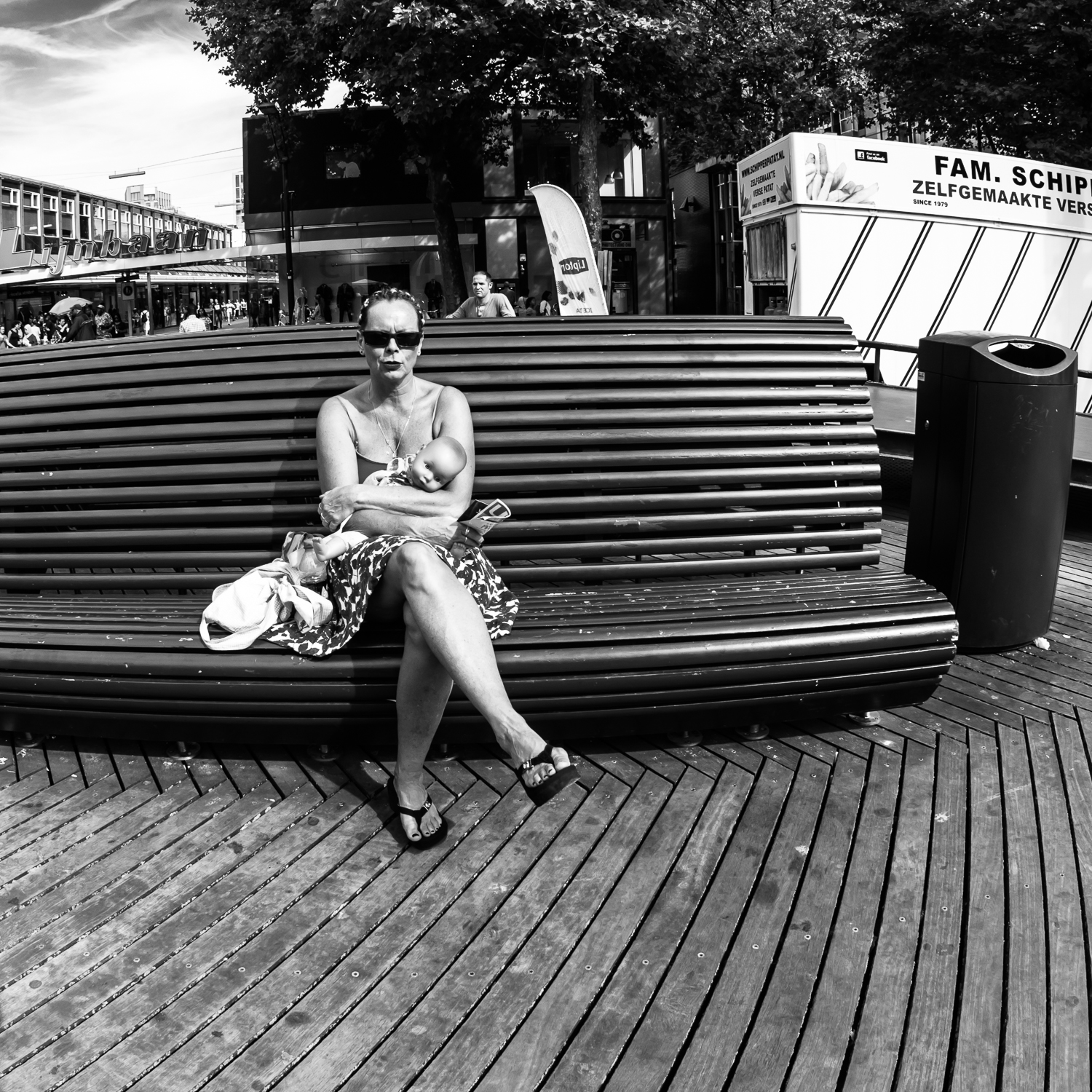 ROTTERDAM SEPTEMBER 2016 Shot taken at the Schouwburgplein in Rotterdam Centre. First I thought the woman was having a baby in her arms. A closer look showed her carrying a doll. Shot with Olympus OMD5 Mark 2 and Olympus 8 mm f/1.8 Fisheye PRO