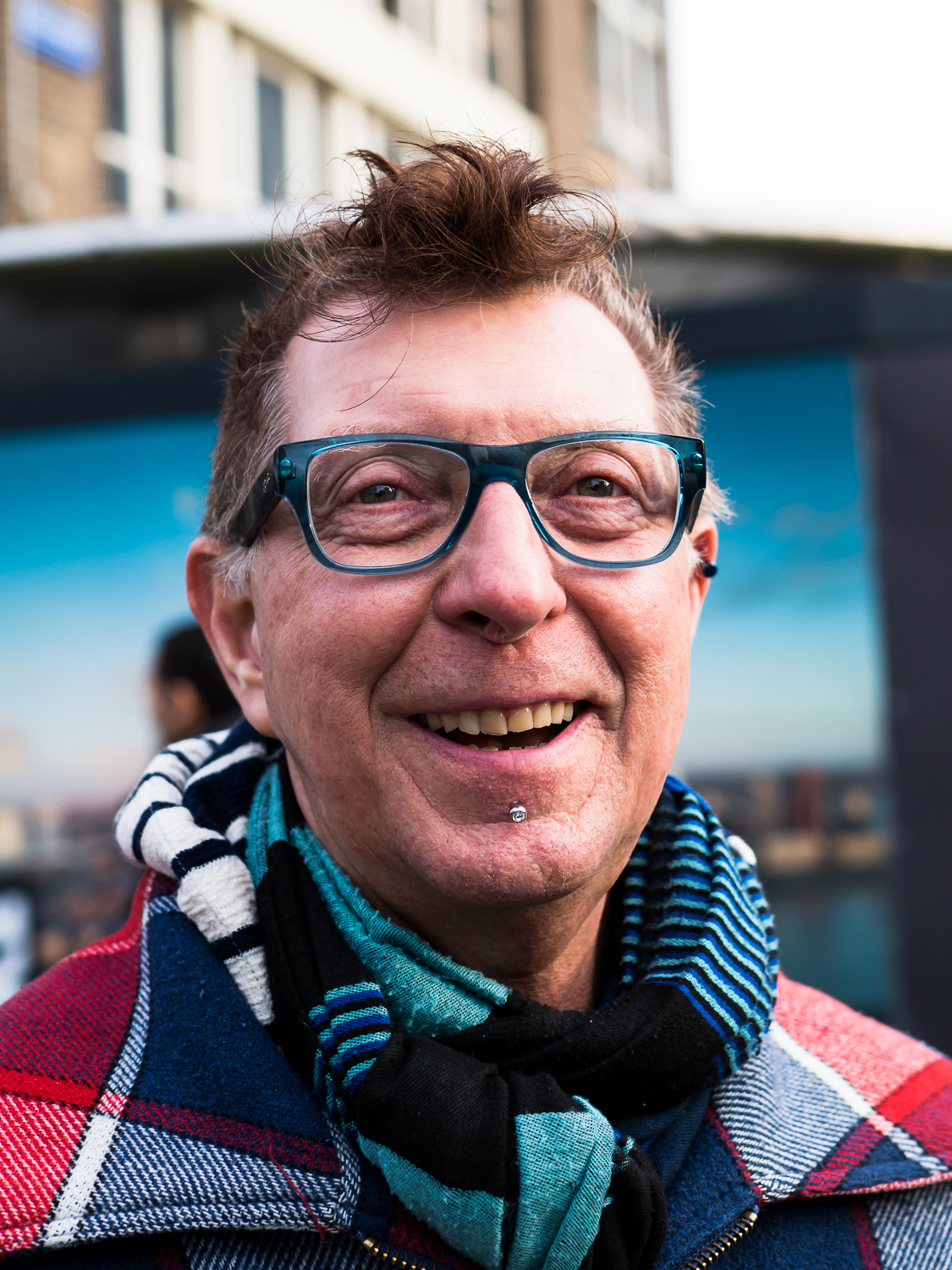 Photo taken in Rotterdam in March 2017. Sometimes I make street portraits with permission of the model. This guy lives in Emmen but was born in Rotterdam. It was a long time since he visited Rotterdam and he told me that he got quite emotional touching the Rotterdam ground again. His name is Eddy Tijssen. His colorful clothes and his friendly open face caught my intention. Shot with Olympus OMD1 Mark 2 and Olympus 25mm f/1.2. The 25mm is perfect for this kind of portraits. Look how sharp it is!