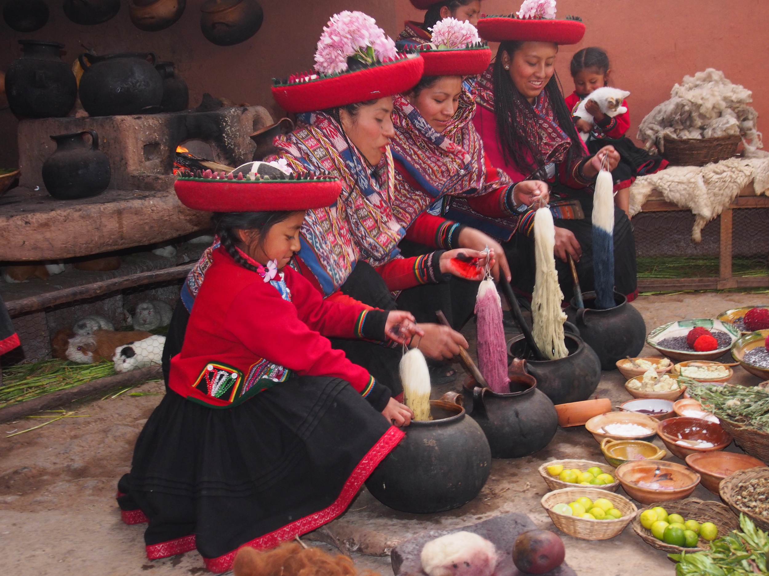 Girls and women demonstrating weaving. Note the guinea pigs in the background.