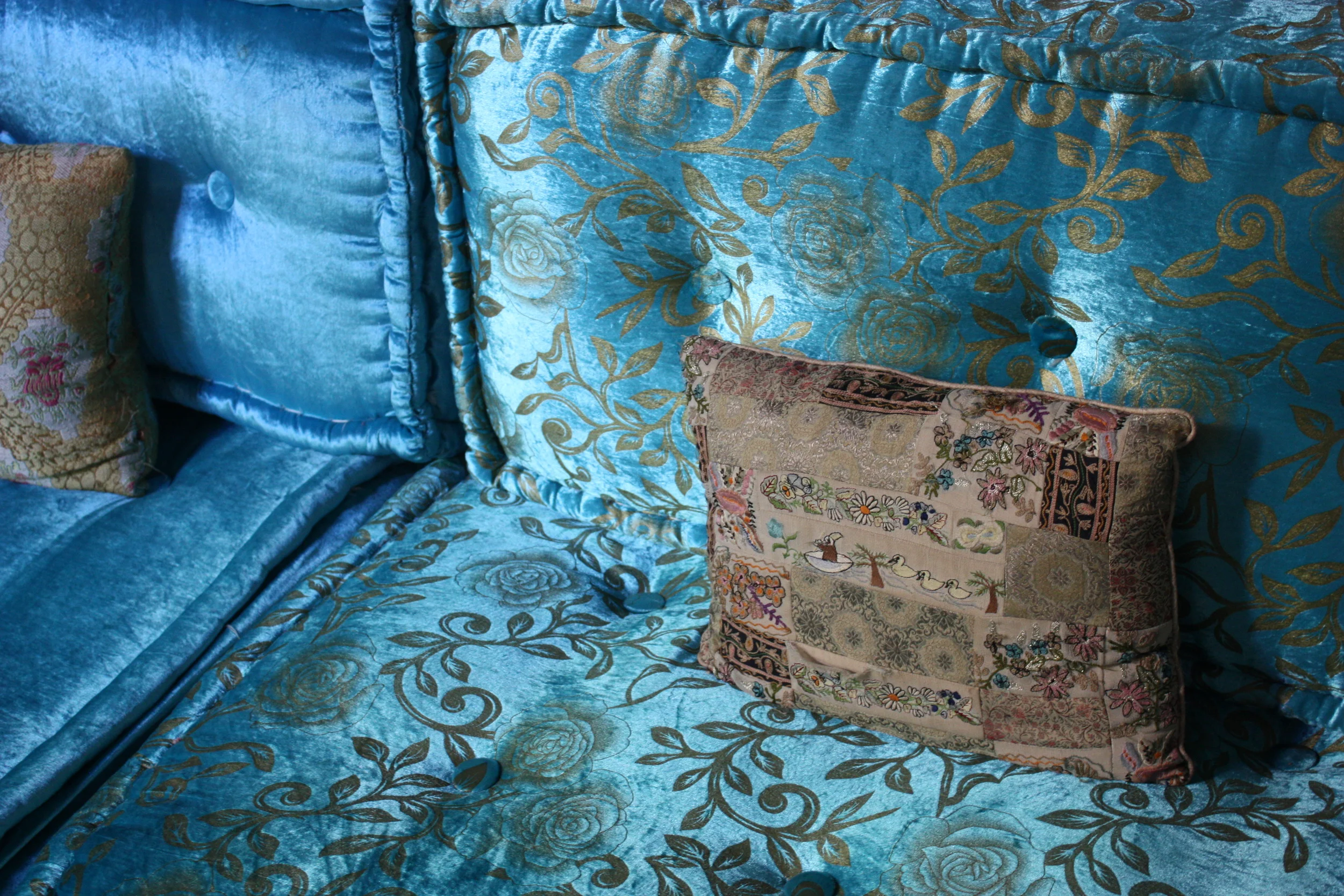 Old-fashioned plush velvets in luscious jewel colors are traditional in the Moroccan version of the divan, here combined with a delightfully embroidered pillow. From a riad salon in the old city of Fez in Morocco.